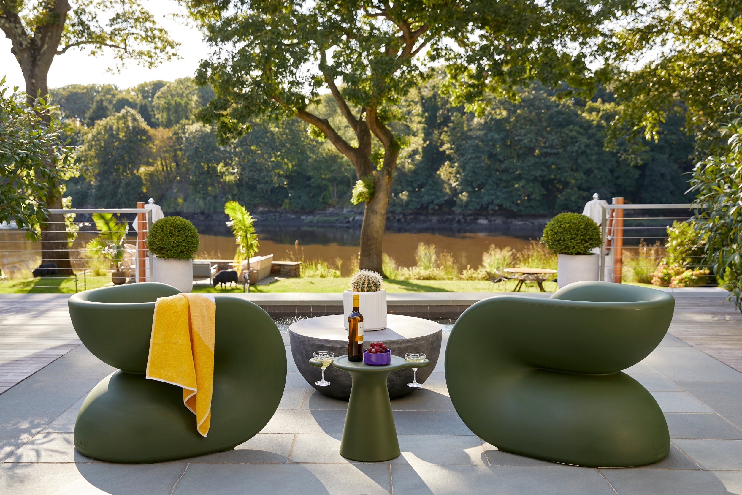 A Heller Fortune Chair in olive green on a patio, rotationally molded from UV-stabilized polyethylene.
