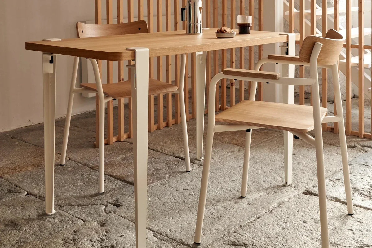 Tiptoe oak dining table set for two on folded-steel legs in a small room