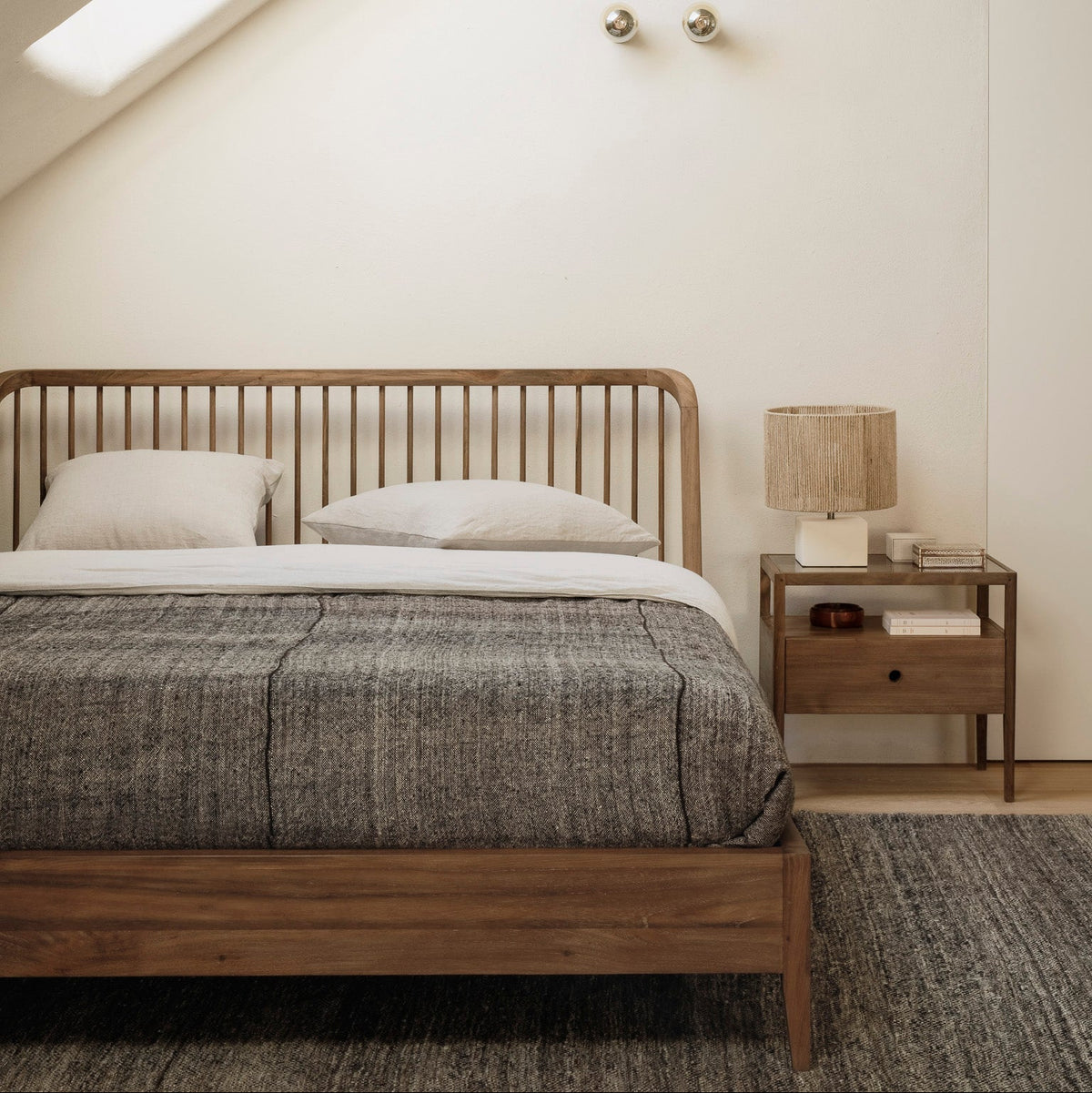 Ethnicraft Oak Spindle bed and matching bedside table in a bright attic bedroom with a wool rug