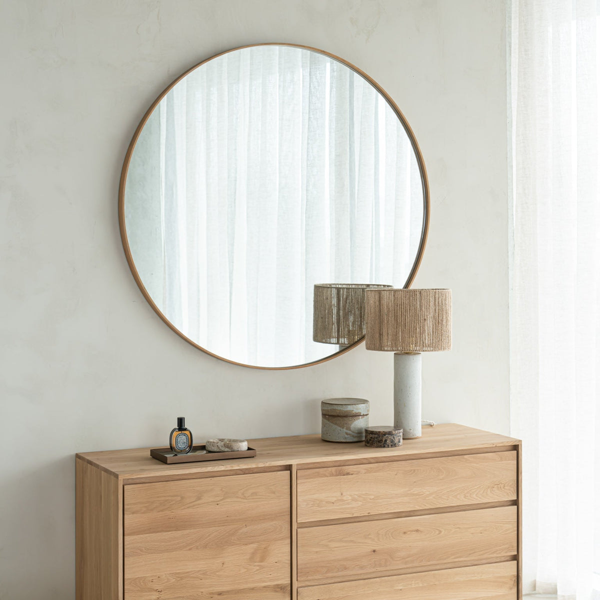 Ethnicraft Layers round wall mirror with an oak frame above an oak Wave sideboard