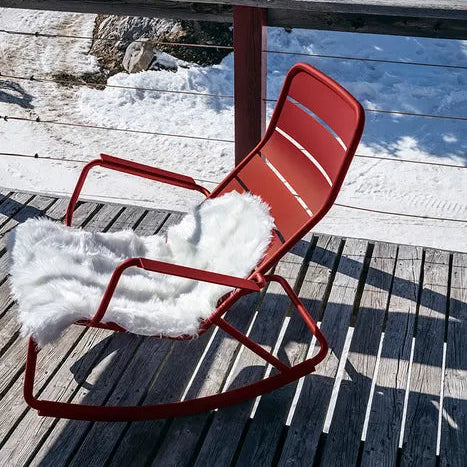 Fermob Luxembourg rocking chair in Chili red with a sheepskin throw on a snowy wooden deck