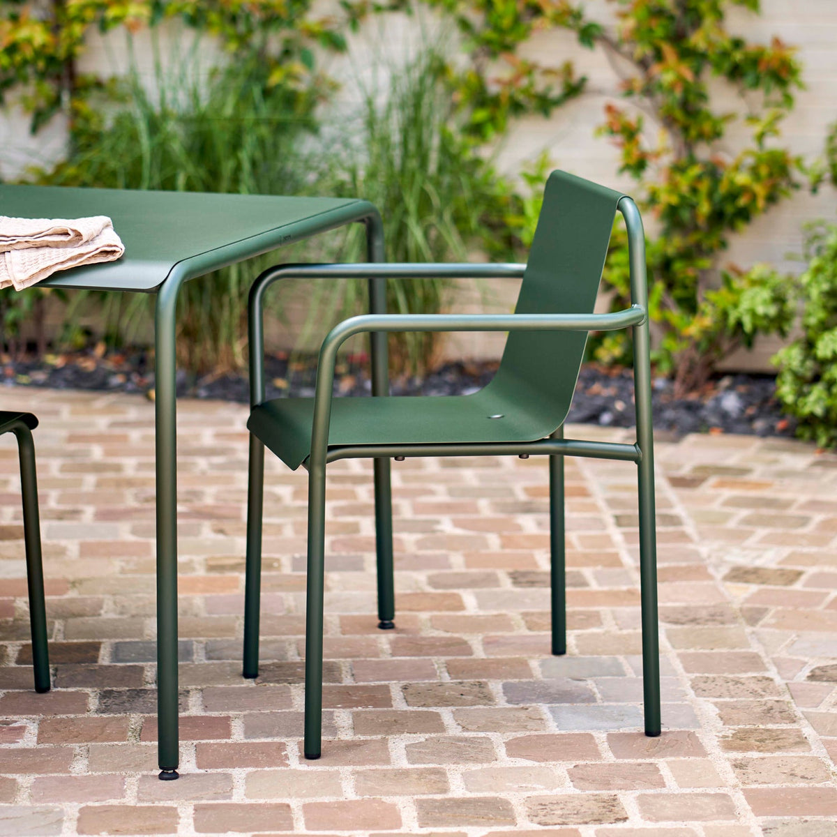 Tiptoe PANORAMA Outdoor Armchair in Forest Green on a brick terrace, powder-coated steel