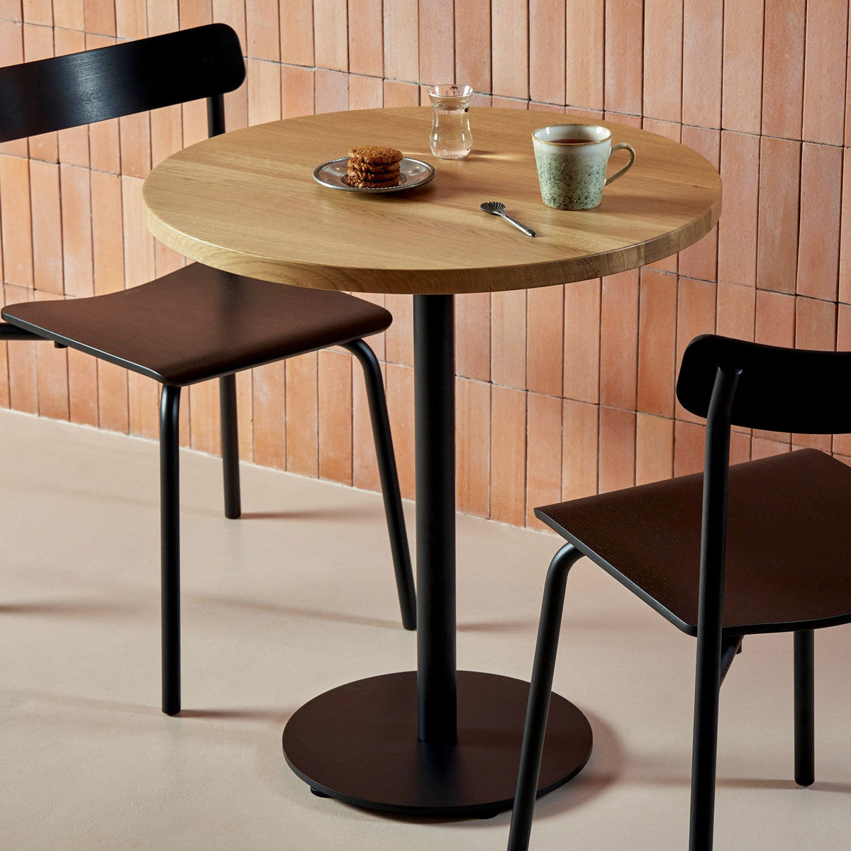 Tiptoe MOKA Bistro Table, round in Graphite Black, styled in a cafe setting, solid oak and powder-coated steel