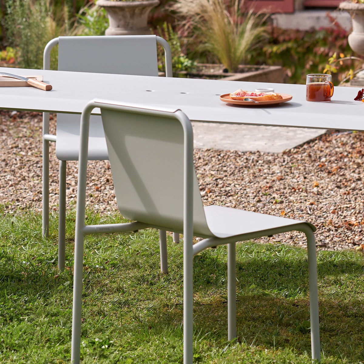 Tiptoe PANORAMA Outdoor Chair in Chalk Gray at a garden table on gravel, powder-coated steel