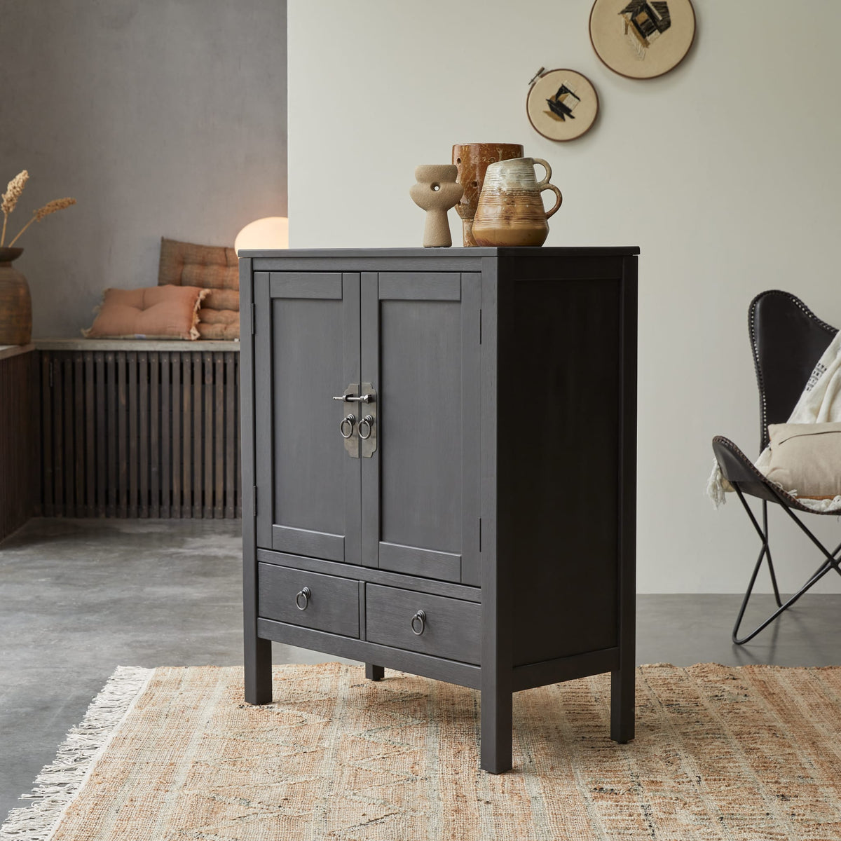 Tikamoon Thaki Black cabinet with two doors and two drawers beside a lounge chair