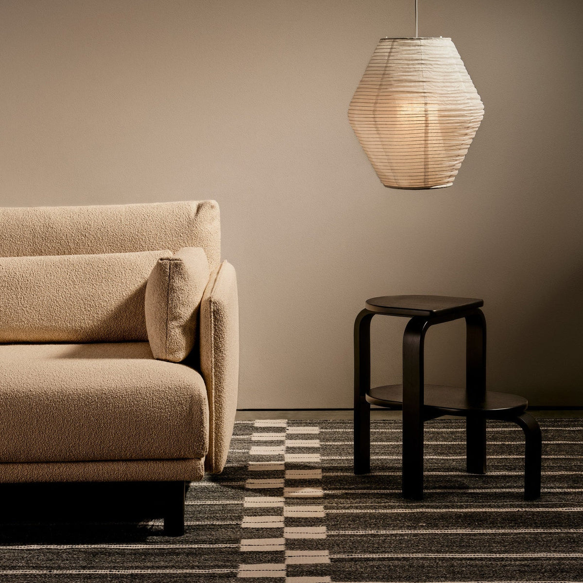 Detail of Case Spine RPET Rug in Warm Grey beside a sofa, recycled PET flat weave