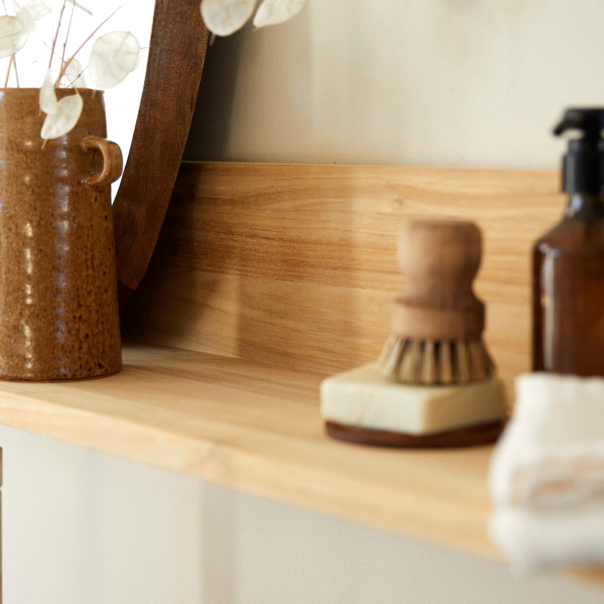 Detail of the Arty teak shelf surface with a brush and pottery