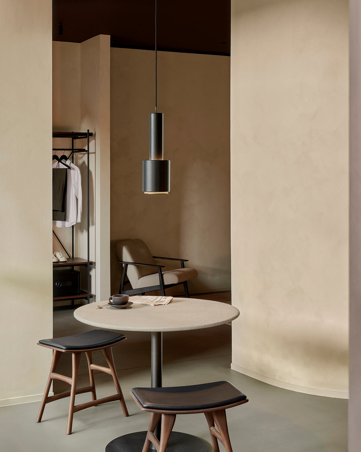 Ethnicraft Blend table in Off White Microcement, styled in a café interior, Dark Bronze metal base