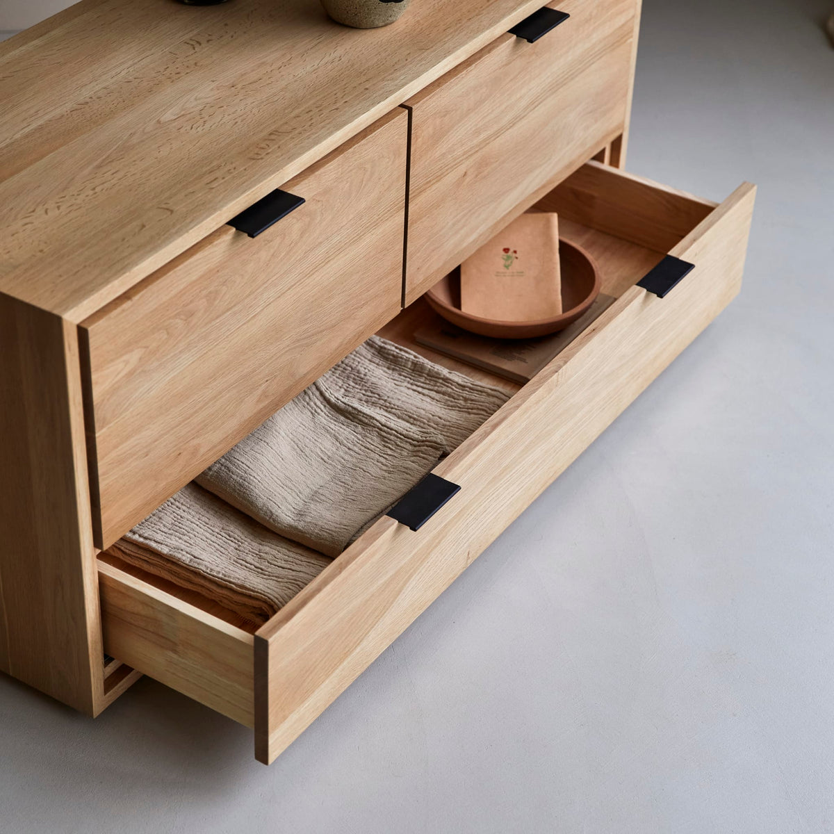 Senson oak TV stand drawer pulled open with folded linens