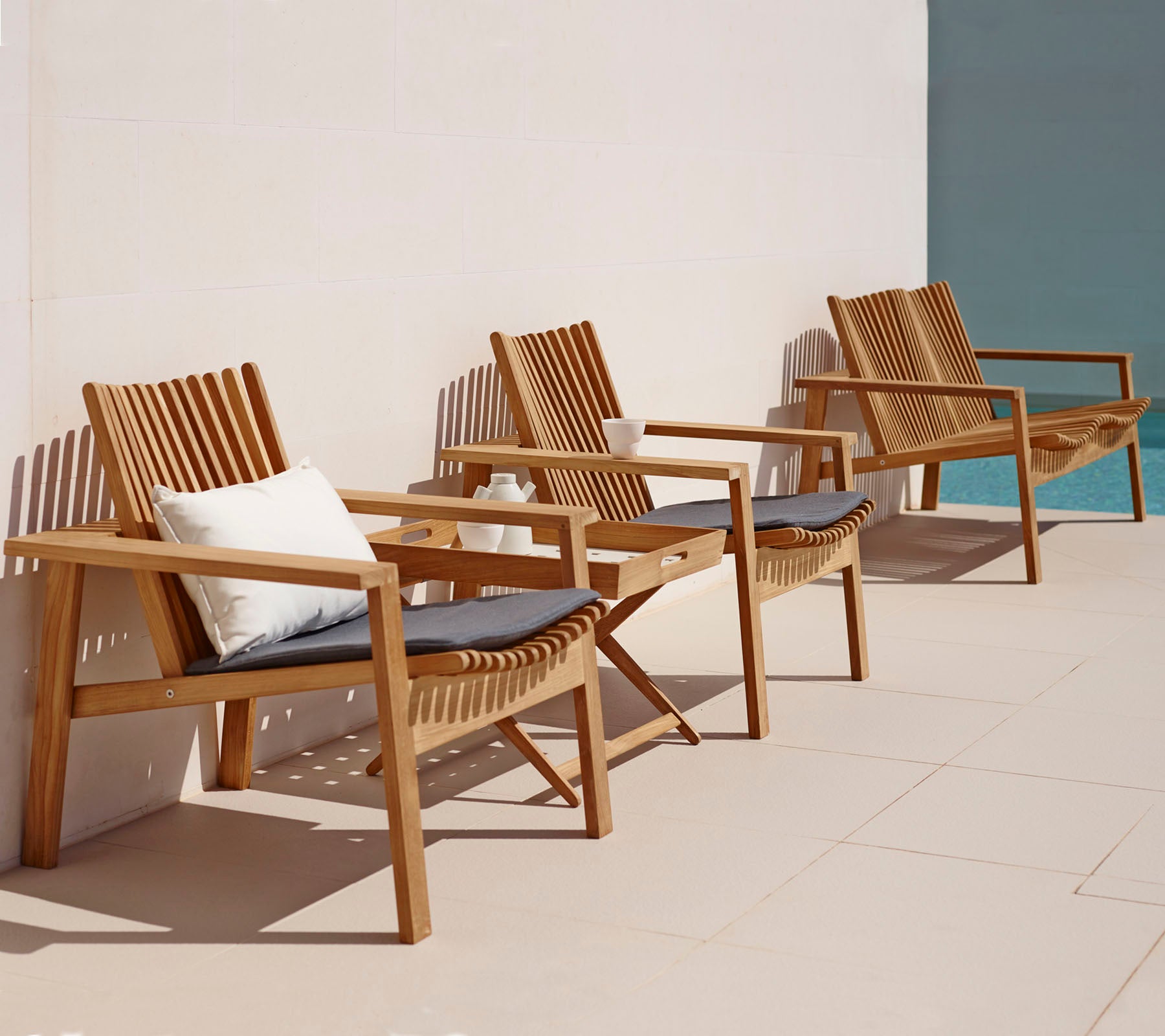 Wooden outdoor chairs with cushions on a tiled patio.