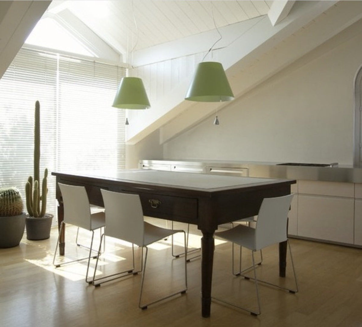 Luceplan Costanza Pendants with green shades over a dining table, styled in an interior setting