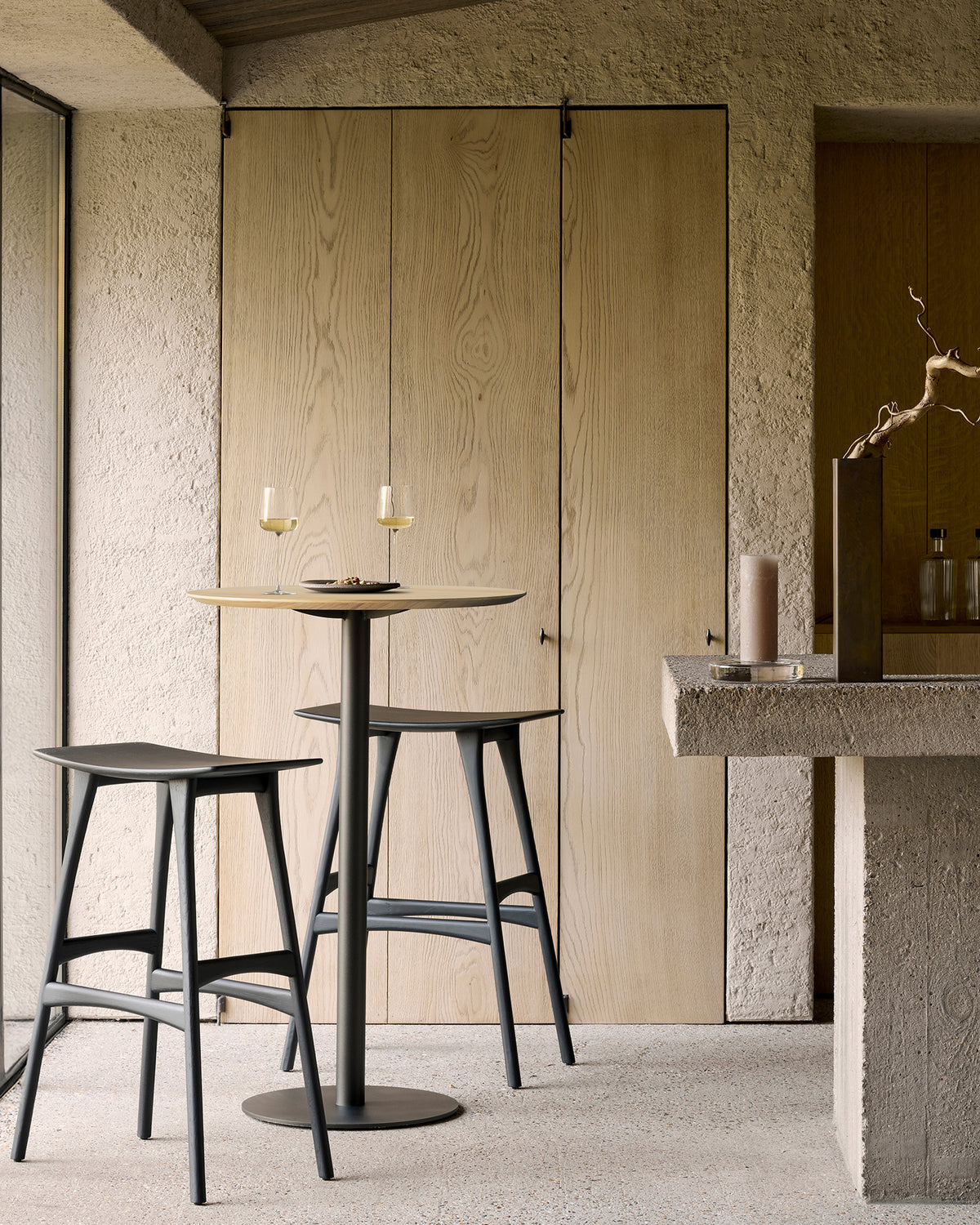 Ethnicraft Blend Bar Table in Oak with Osso bar stools, styled in an interior setting, solid oak top on metal base