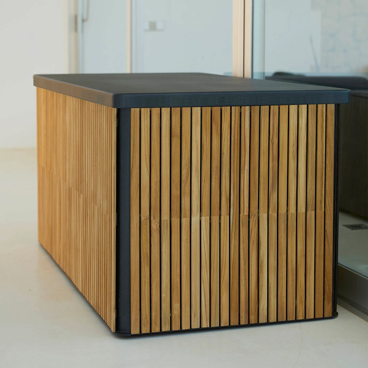 Cane-line Combine large cushion box in teak with a Lava Gray lid on a terrace