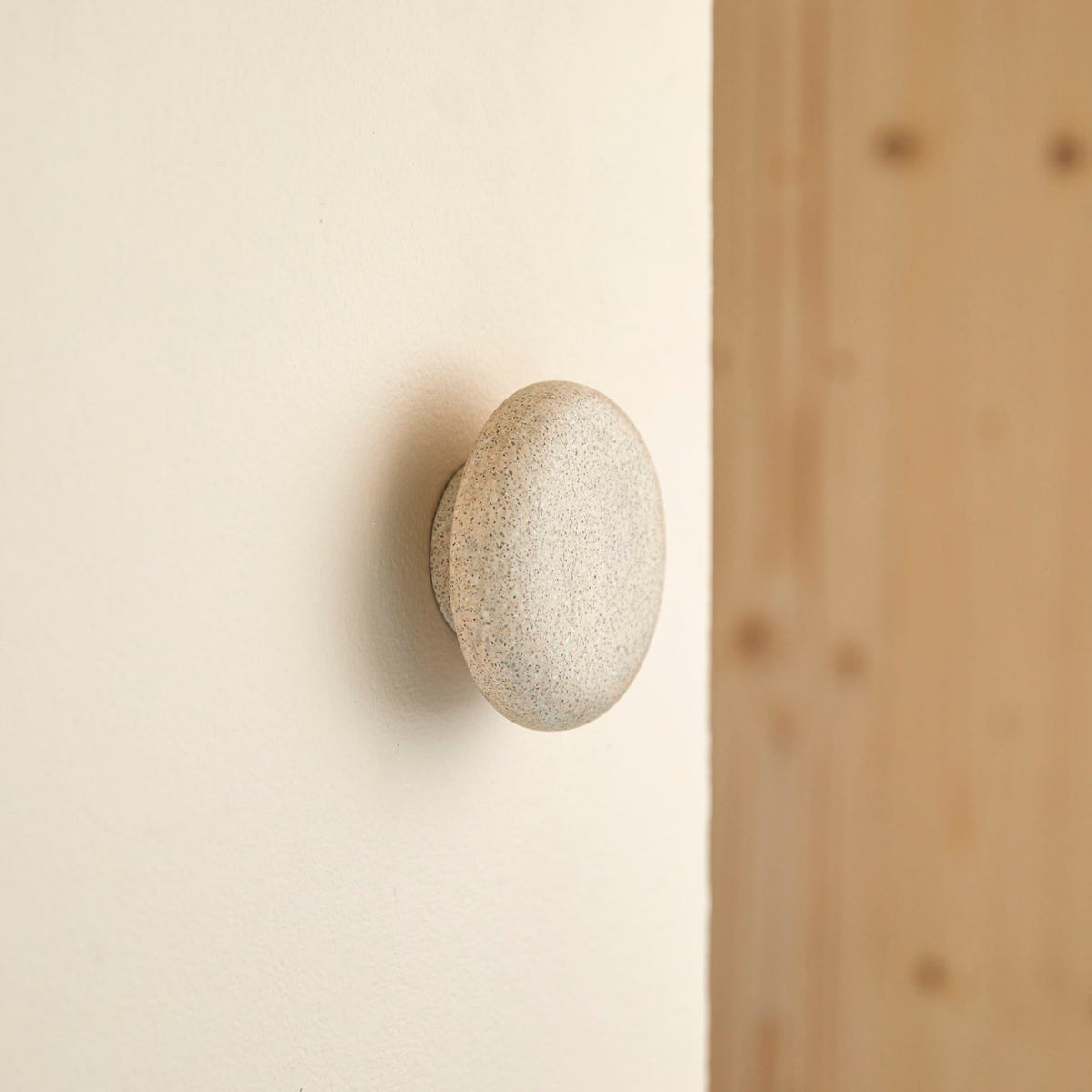 Tikamoon Eda wall hook in cream terrazzo, front view of the speckled face