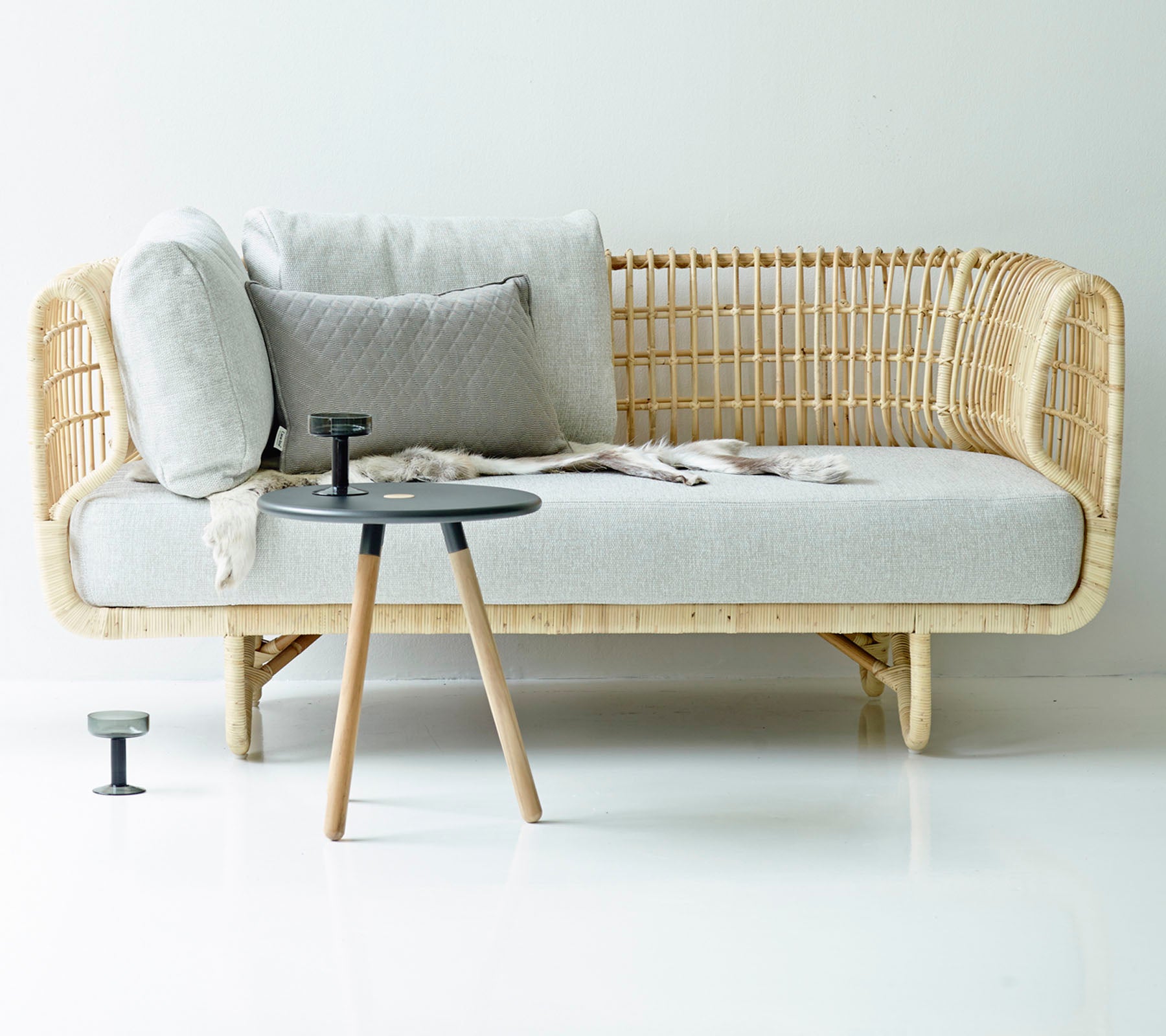 Wicker sofa with cushions and a small table on a white background
