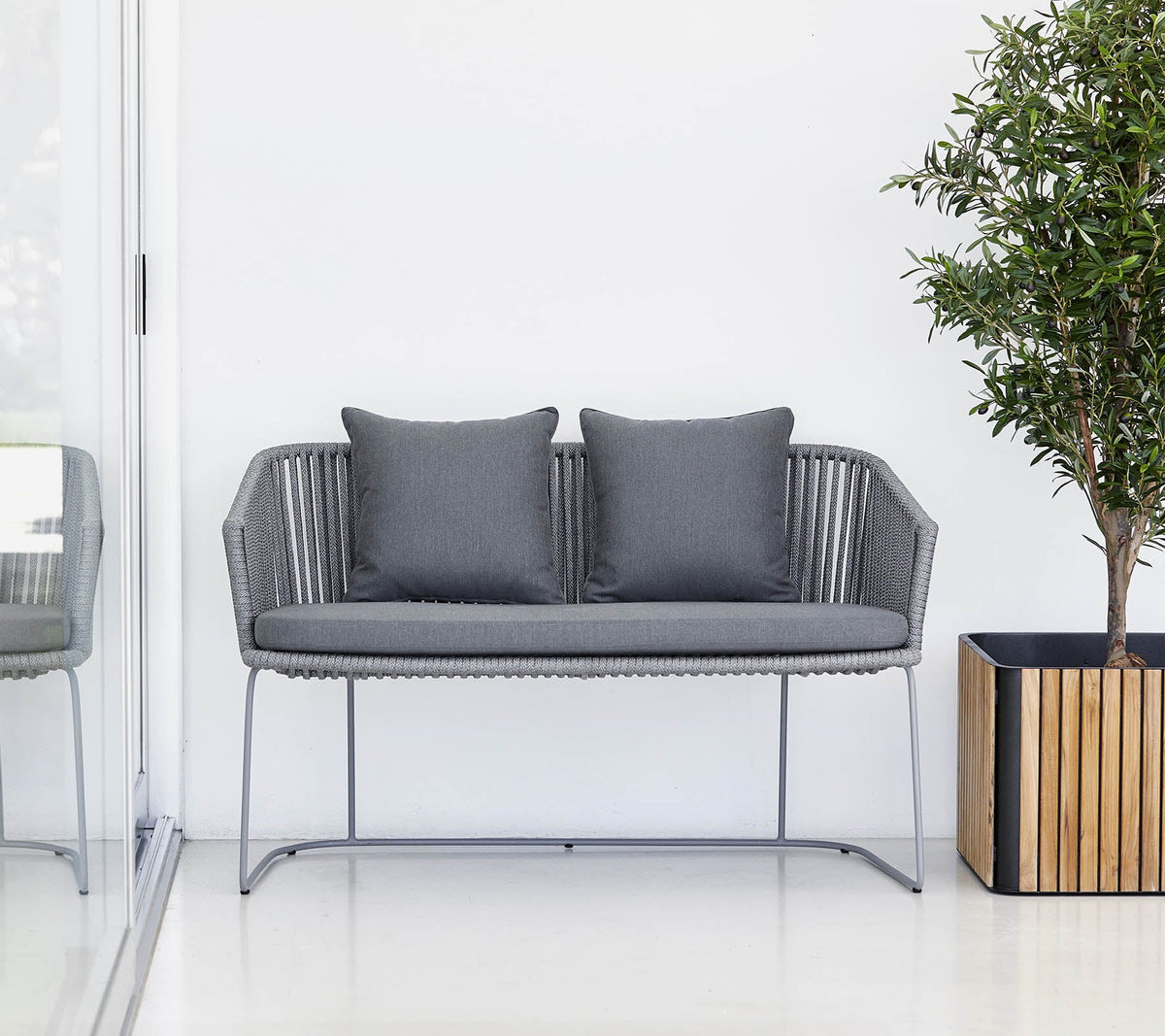 Cane-line Moments Bench in Grey Soft Rope beside a planter, styled on a terrace, open-weave polypropylene