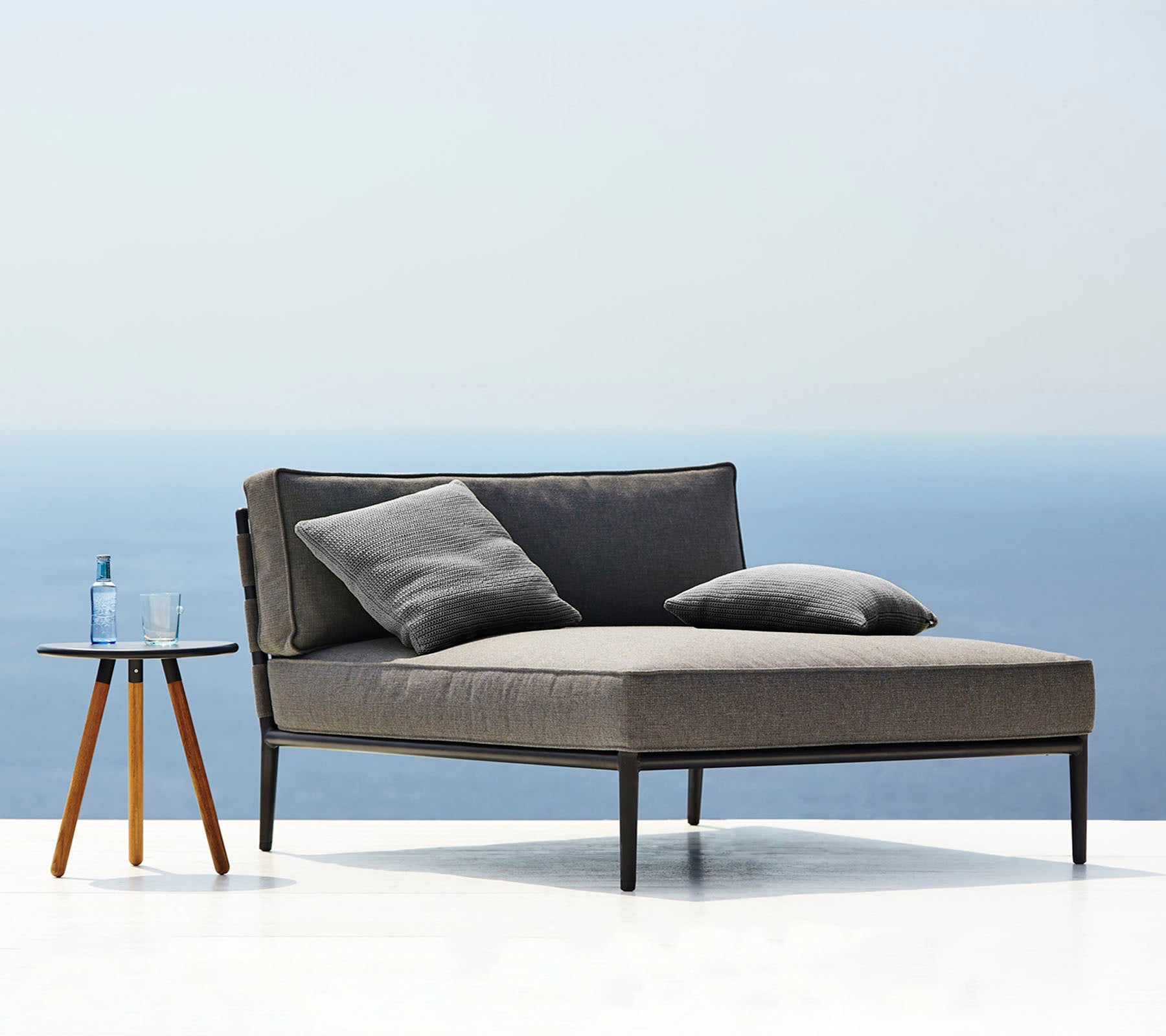 Modern gray sofa with cushions on a white surface and light blue background