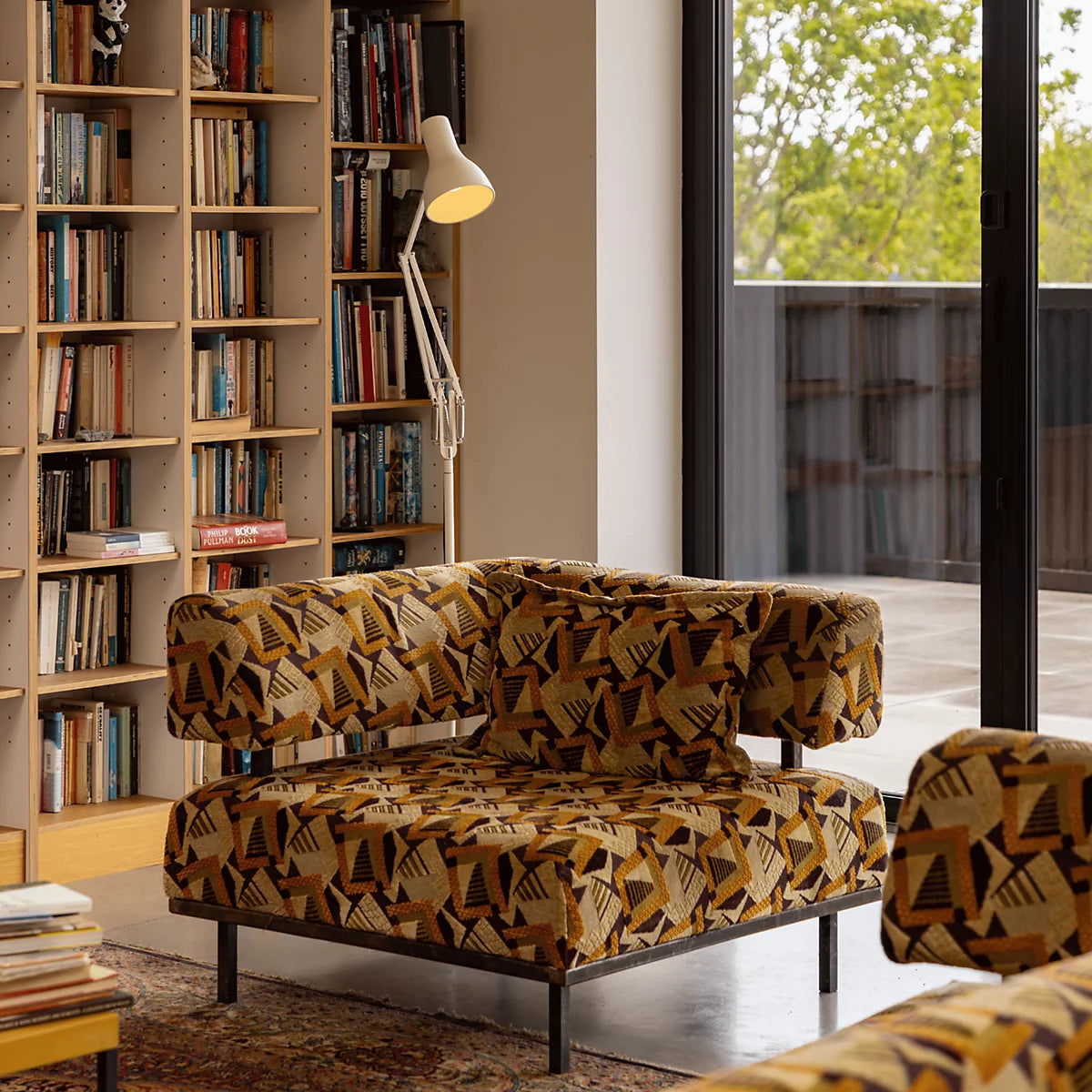 Anglepoise Type 75 floor lamp in white beside a patterned sofa in a book-lined room