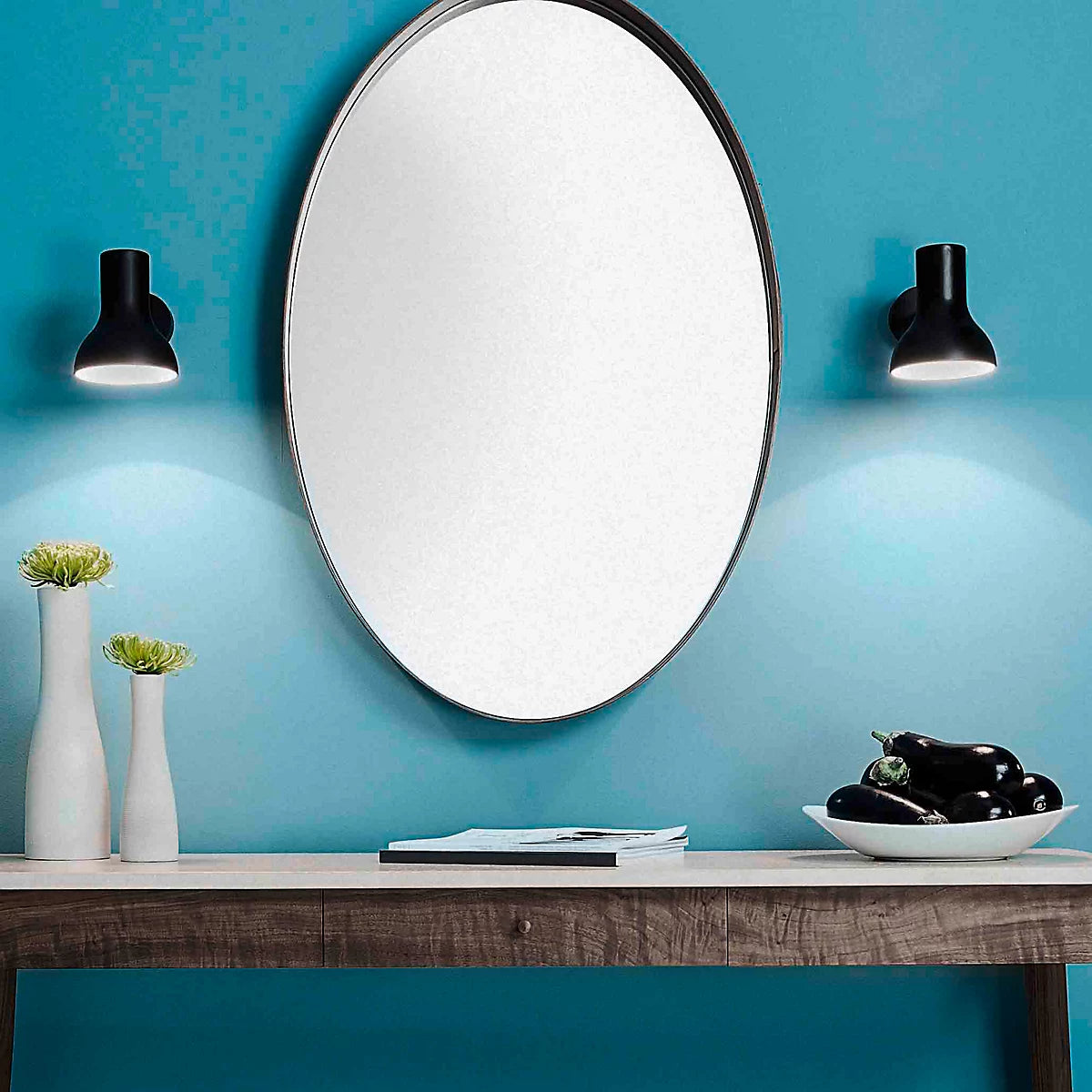 Two Anglepoise Type 75 Mini wall lights in Jet Black either side of a round mirror on a blue wall