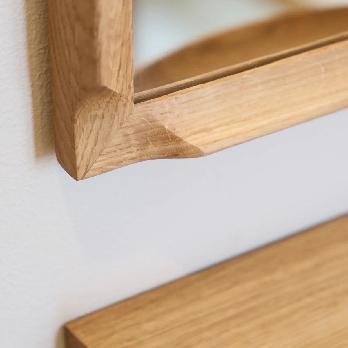 Detail of the Aakjaer Arcus Mirror's rounded solid oak corner above an Arcus Console Shelf