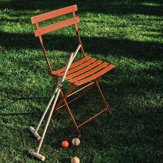 Fermob Bistro Metal Chair in Candied Orange styled in a Mediterranean setting, the 1889 Parisian cafe archetype