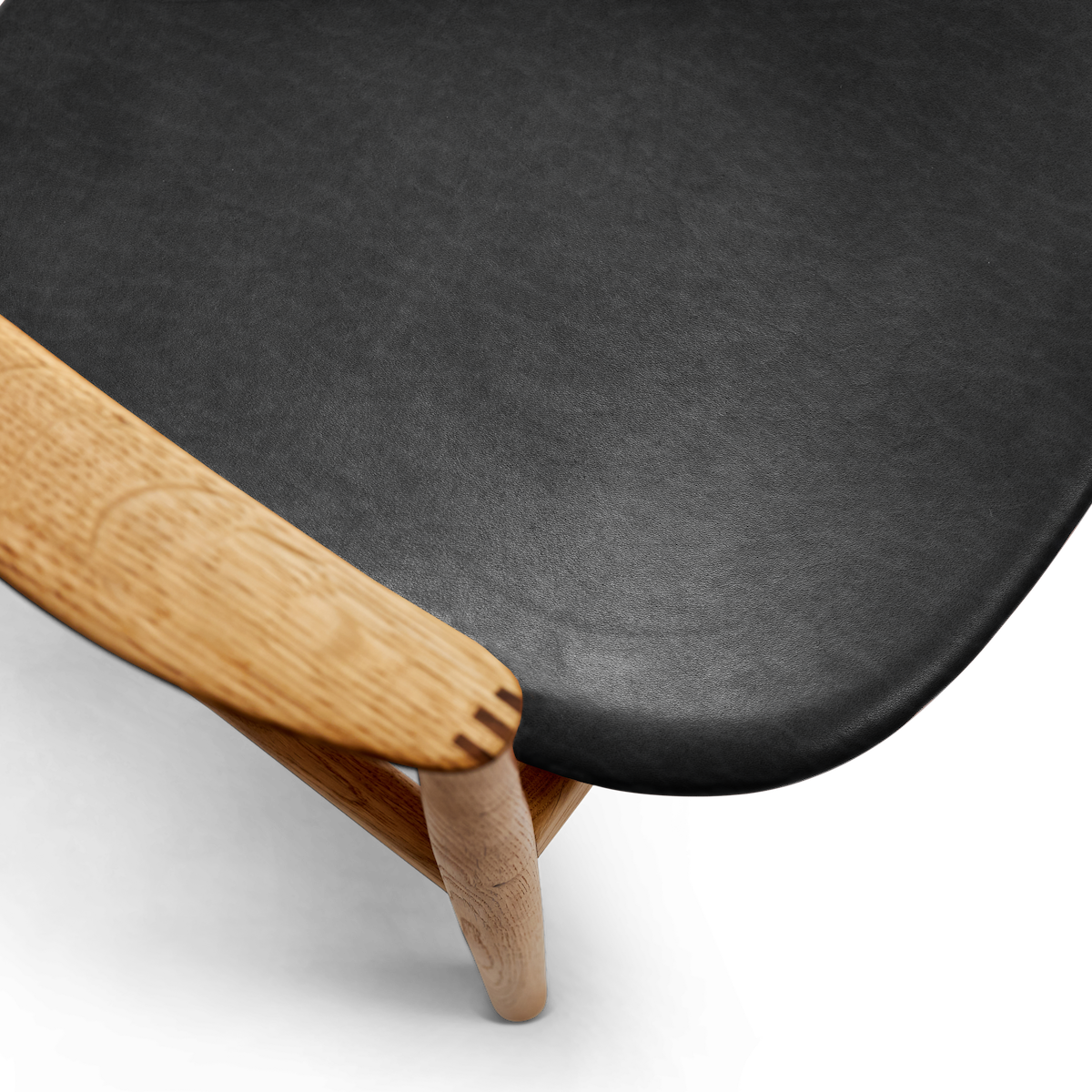 Detail of Bent Hansen Asger Dining Chair showing the black leather seat corner