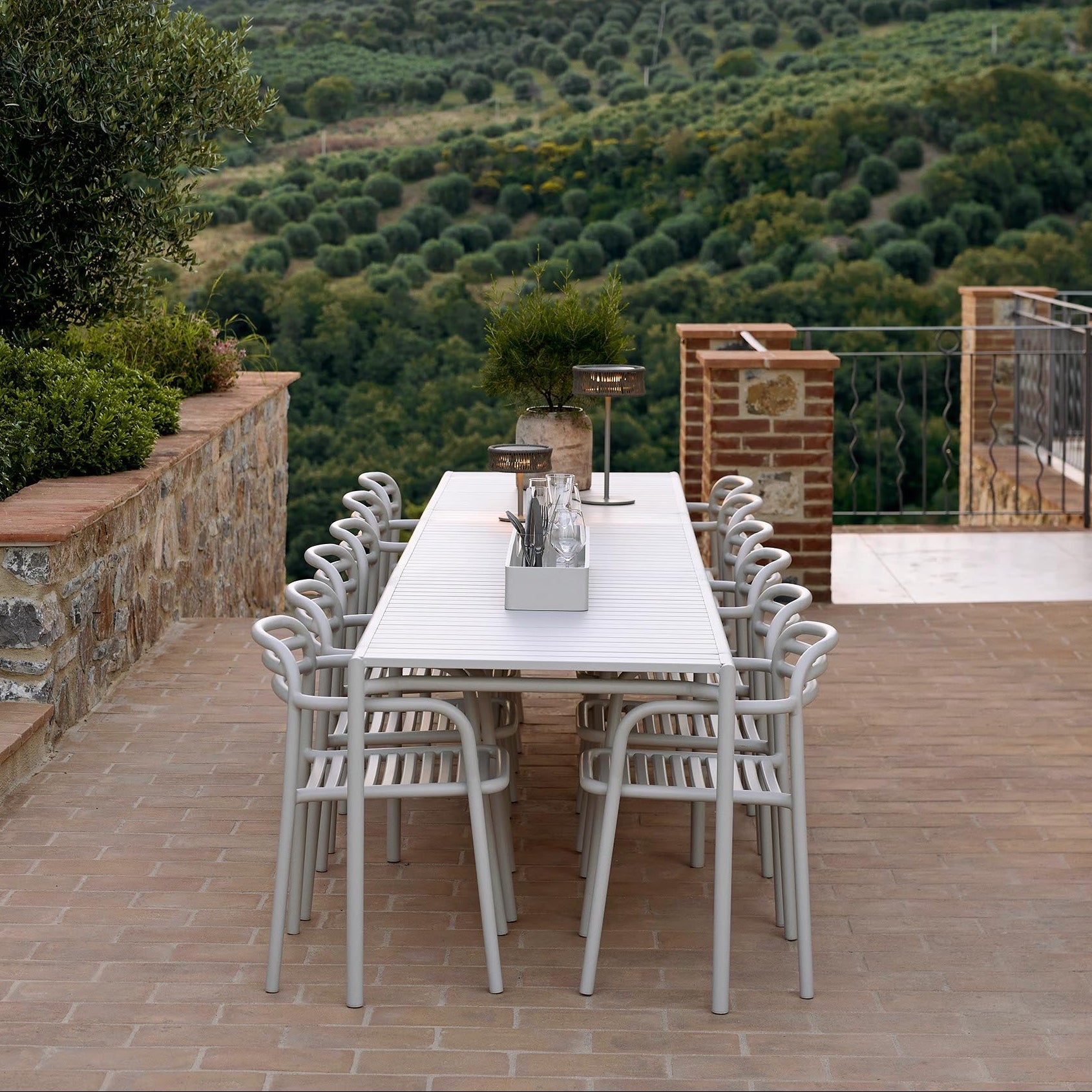 Outdoor dining area with table and chairs on a wooden deck overlooking greenery.
