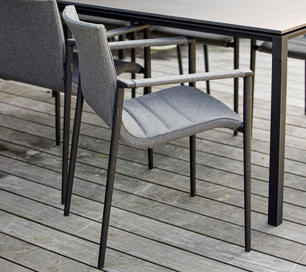 Cane-line Core Armchair in gray beside a dining table, styled outdoors, aluminum with AirTouch fabric
