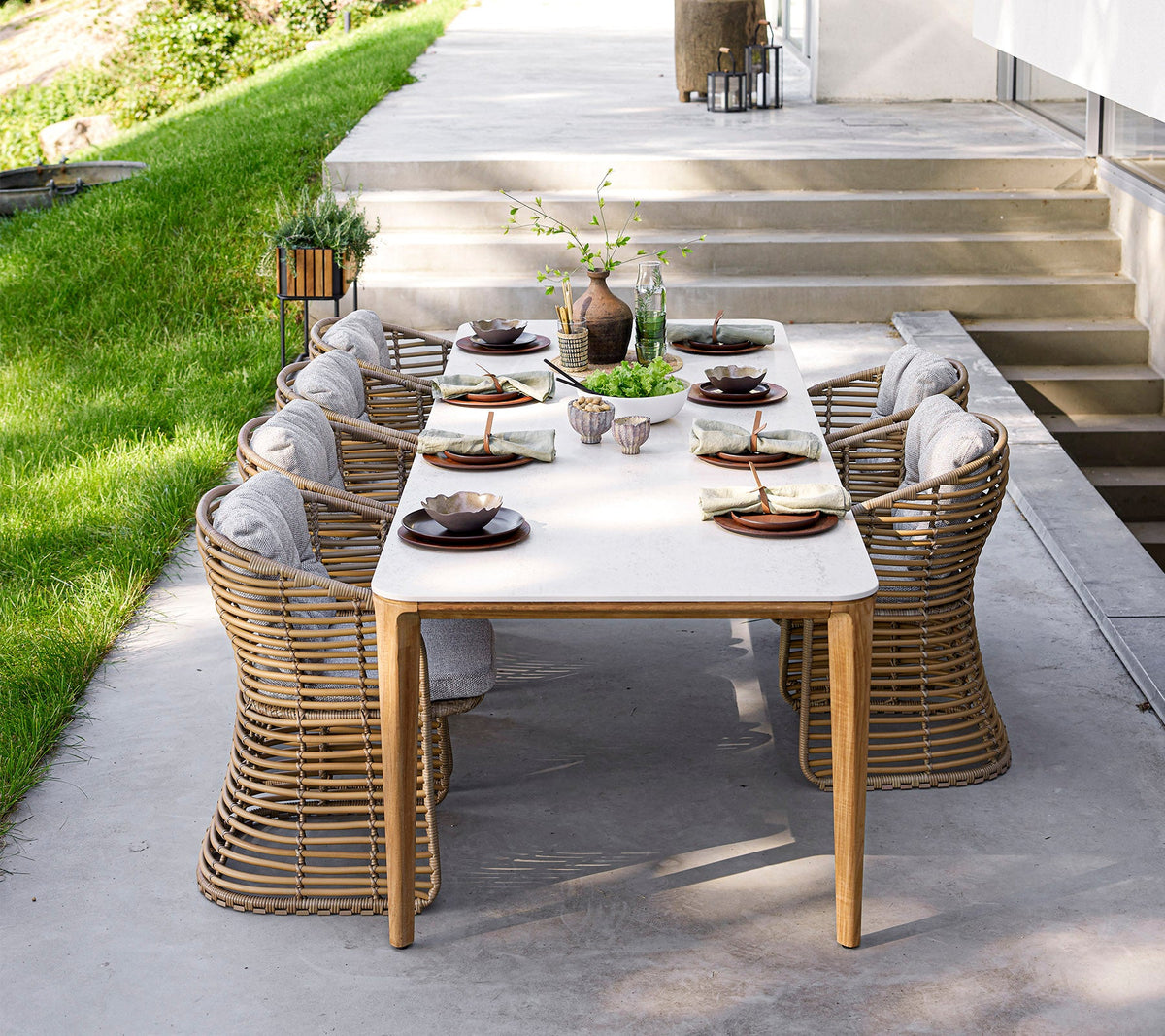 Cane-line Basket Dining Chairs in hand-woven Cane-line Weave at a laid dining table, styled outdoors