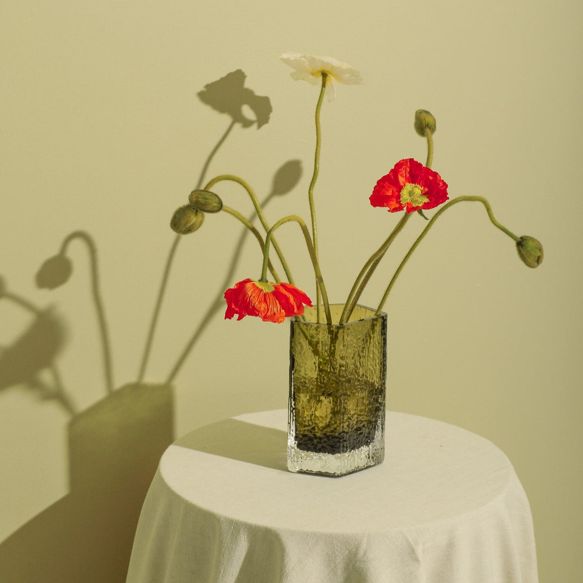 Case Causeway Vase Small in Olive, styled with flowers against a green wall, blown glass