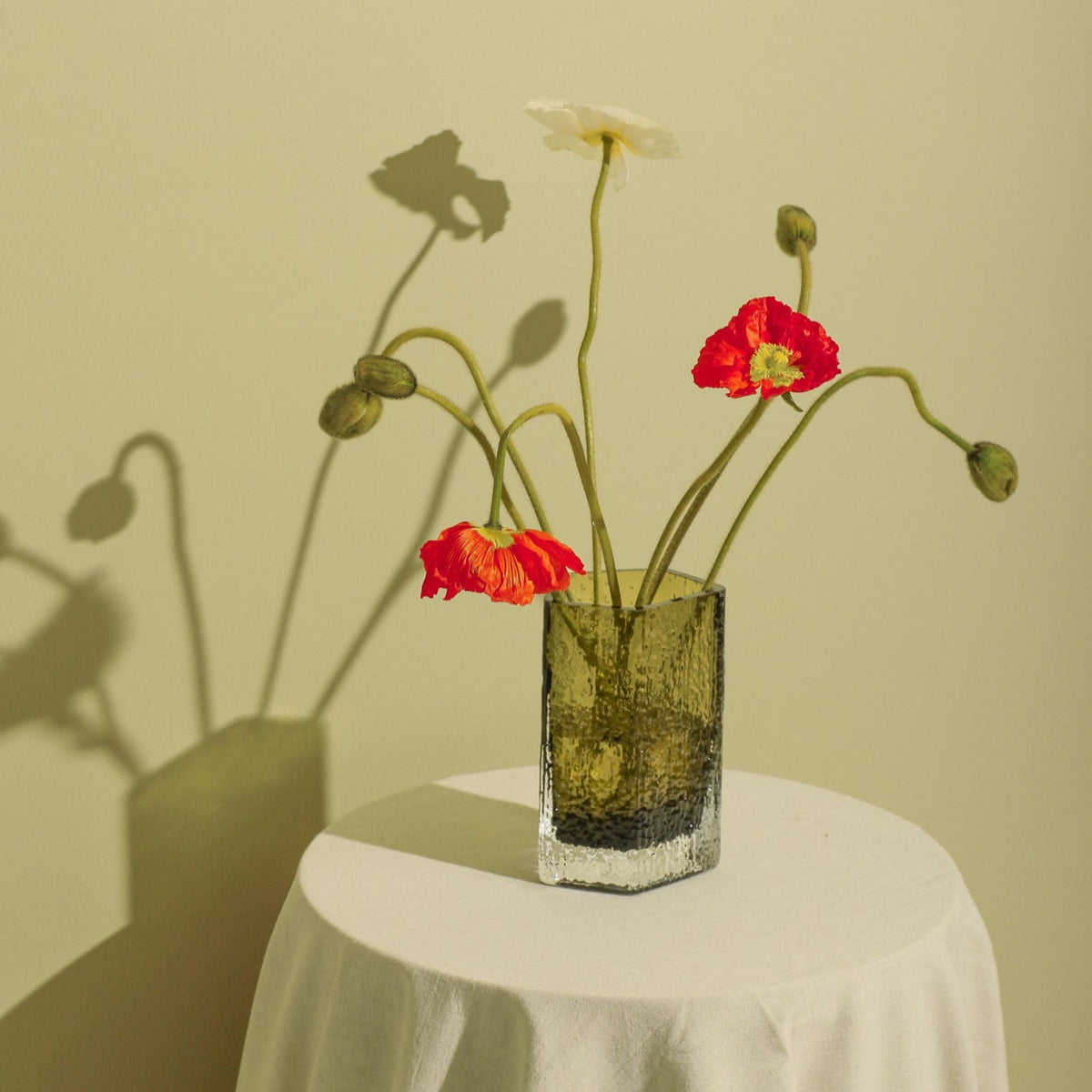 Case Causeway Vase Small in Olive, styled with flowers against a green wall, blown glass