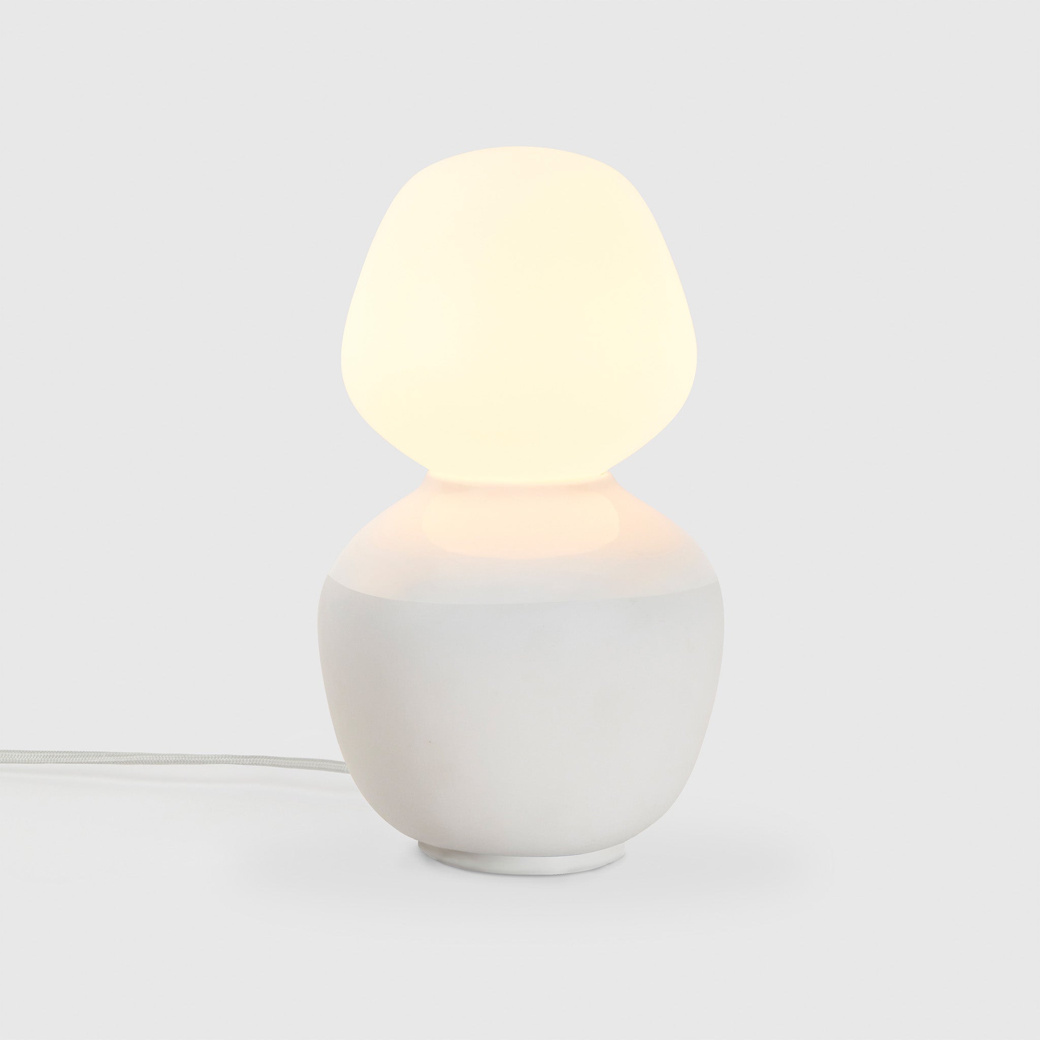Tala Reflection Enno Table Lamp, lit, on grey background