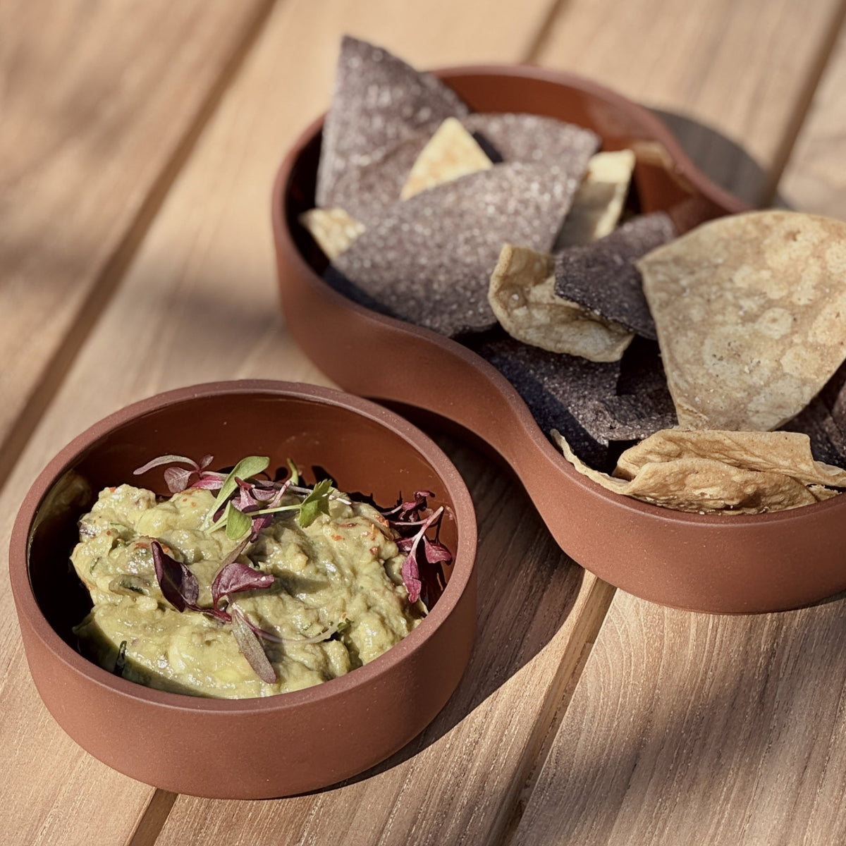 Case Dip Bowl in Brown, styled on a teak table with guacamole and chips, solid-colored porcelain