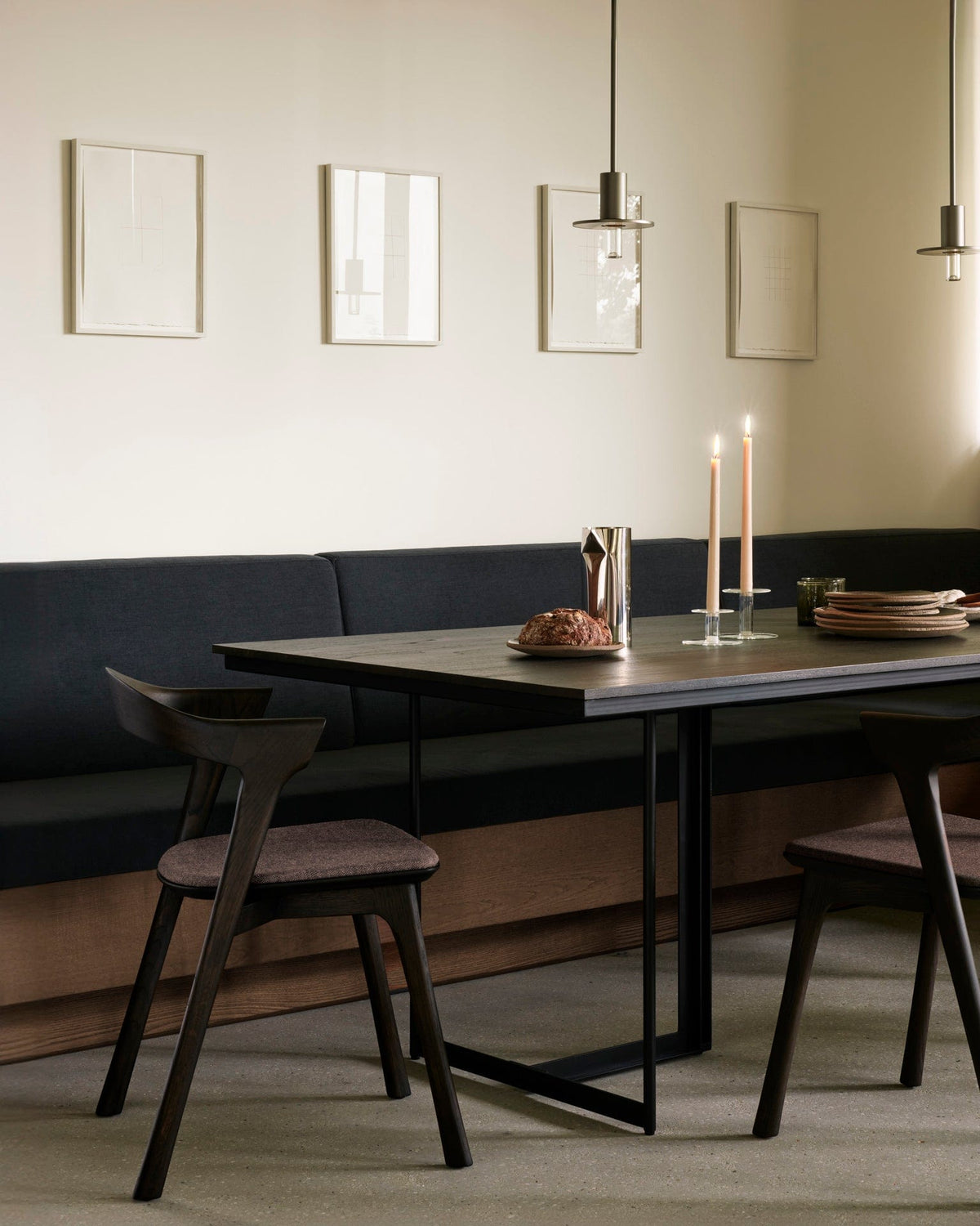 Ethnicraft Tacet Dining Table in dark brown teak set for dinner, styled in an interior setting, black metal base