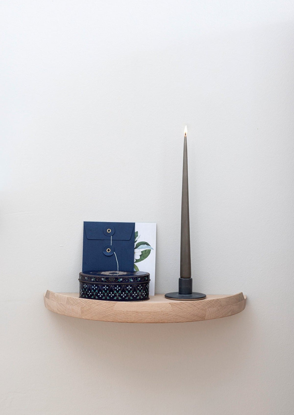 Aakjaer Arcus Console Shelf in white oiled oak holding a candlestick, a box and cards