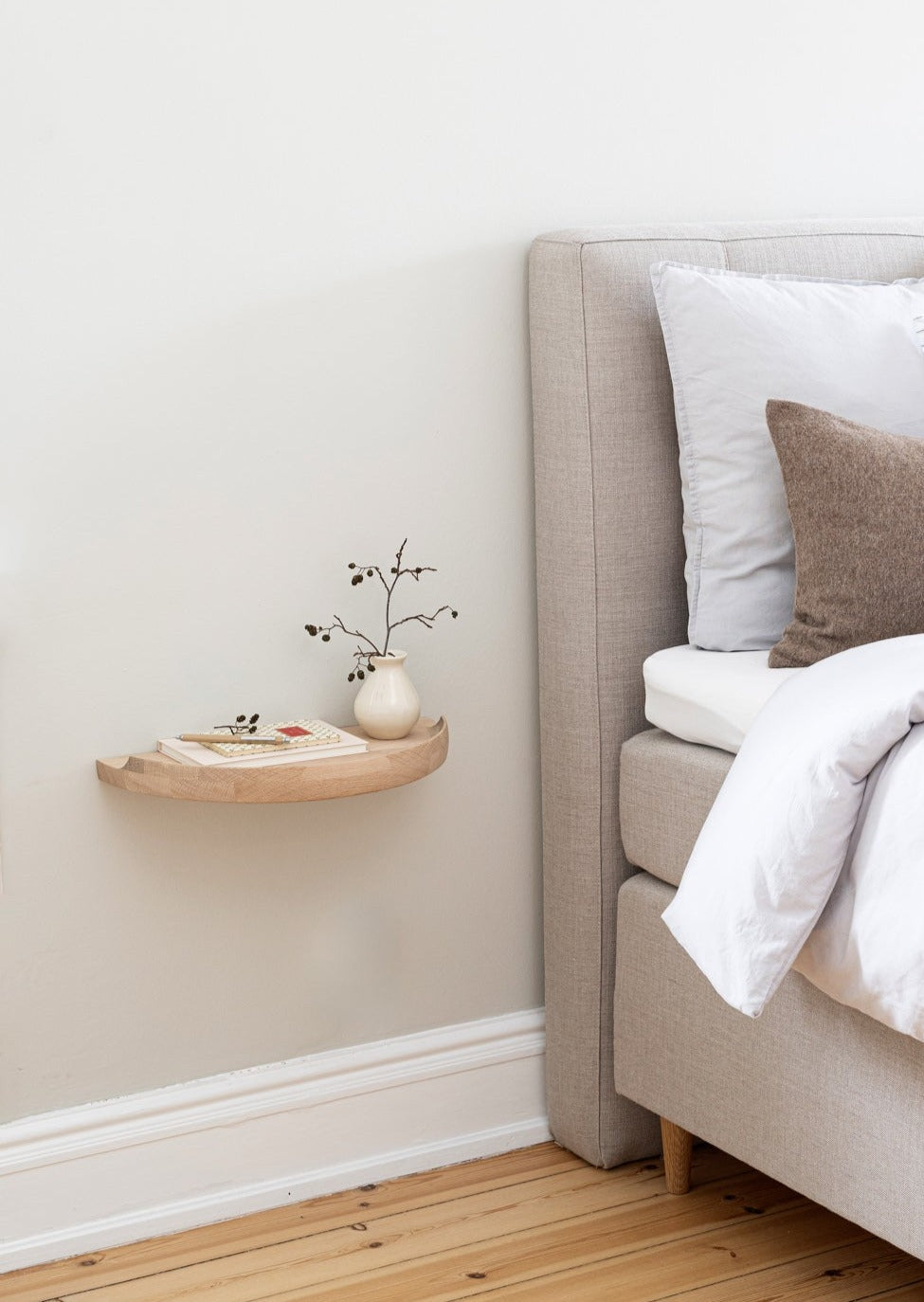 Aakjaer Arcus Console Shelf in white oiled oak mounted beside a bed as a nightstand
