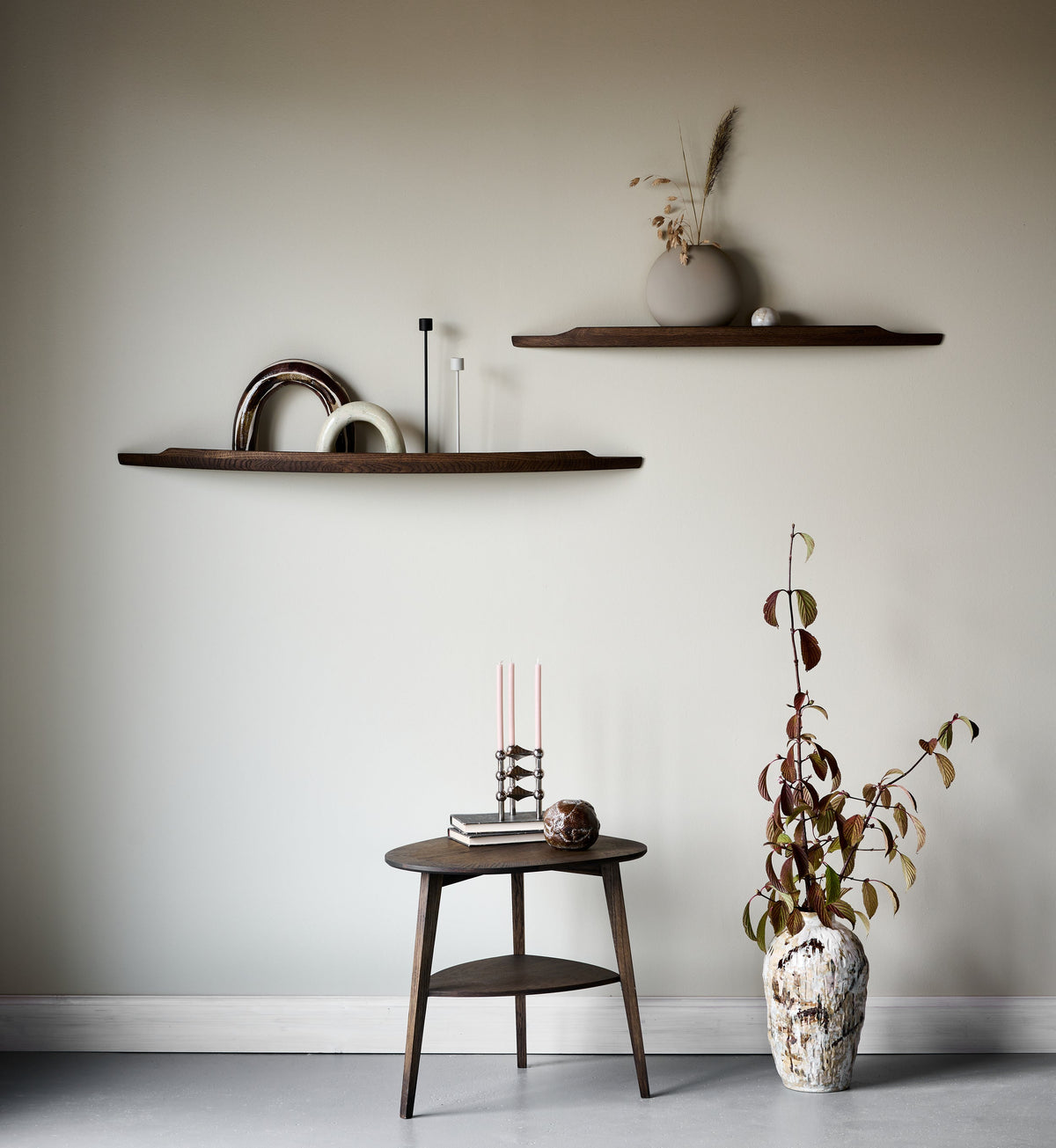 Two Aakjaer Arcus shelves in smoked oak above a small side table and dried flowers
