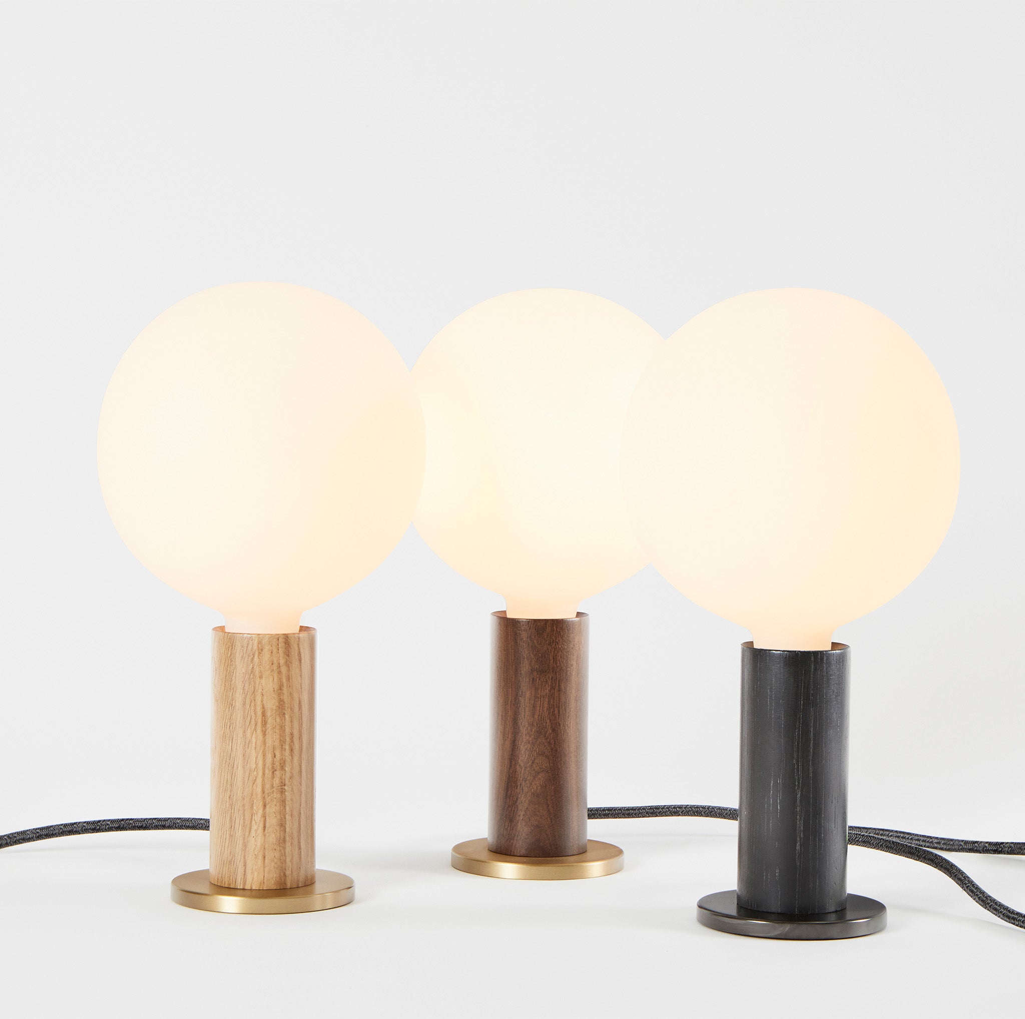 Knuckle Table Lamp trio in Walnut, Oak, and Blackened Oak with Sphere bulb