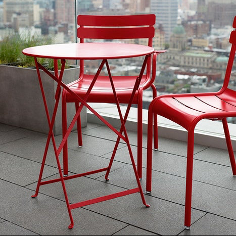Fermob Bistro Red metal table and chairs on a balcony with city skyline in the background