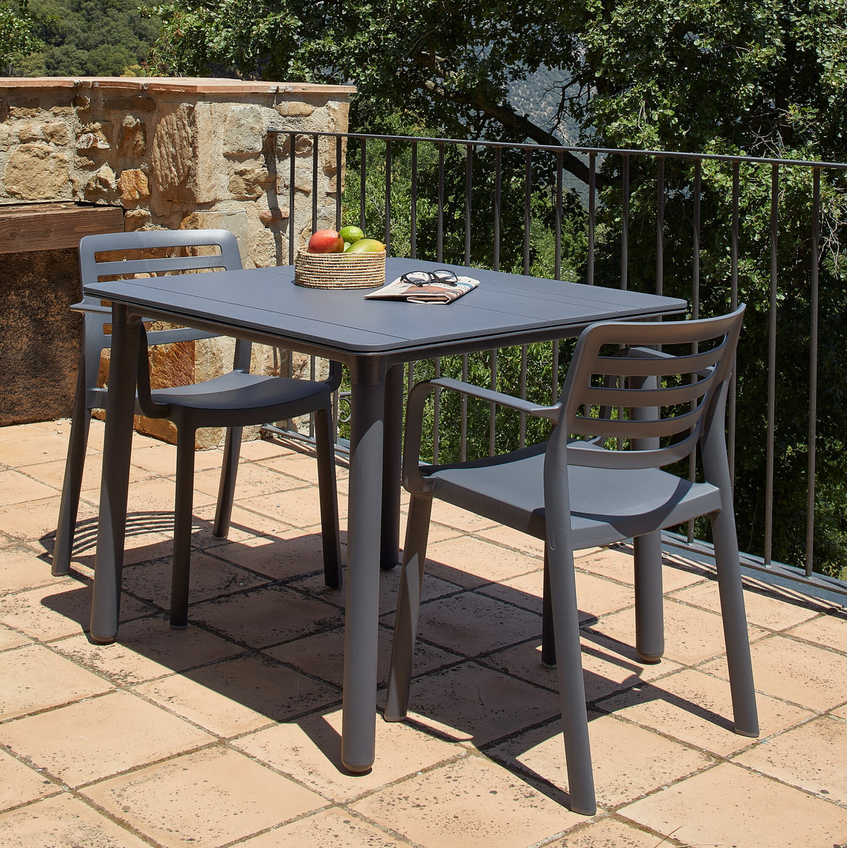 Garbar Wind Armchairs in Dark Grey at a table on a sunny stone terrace