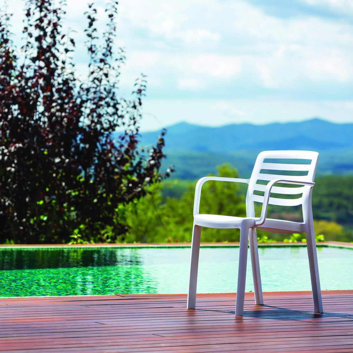 Garbar Wind Armchair in White on a poolside deck with mountain views