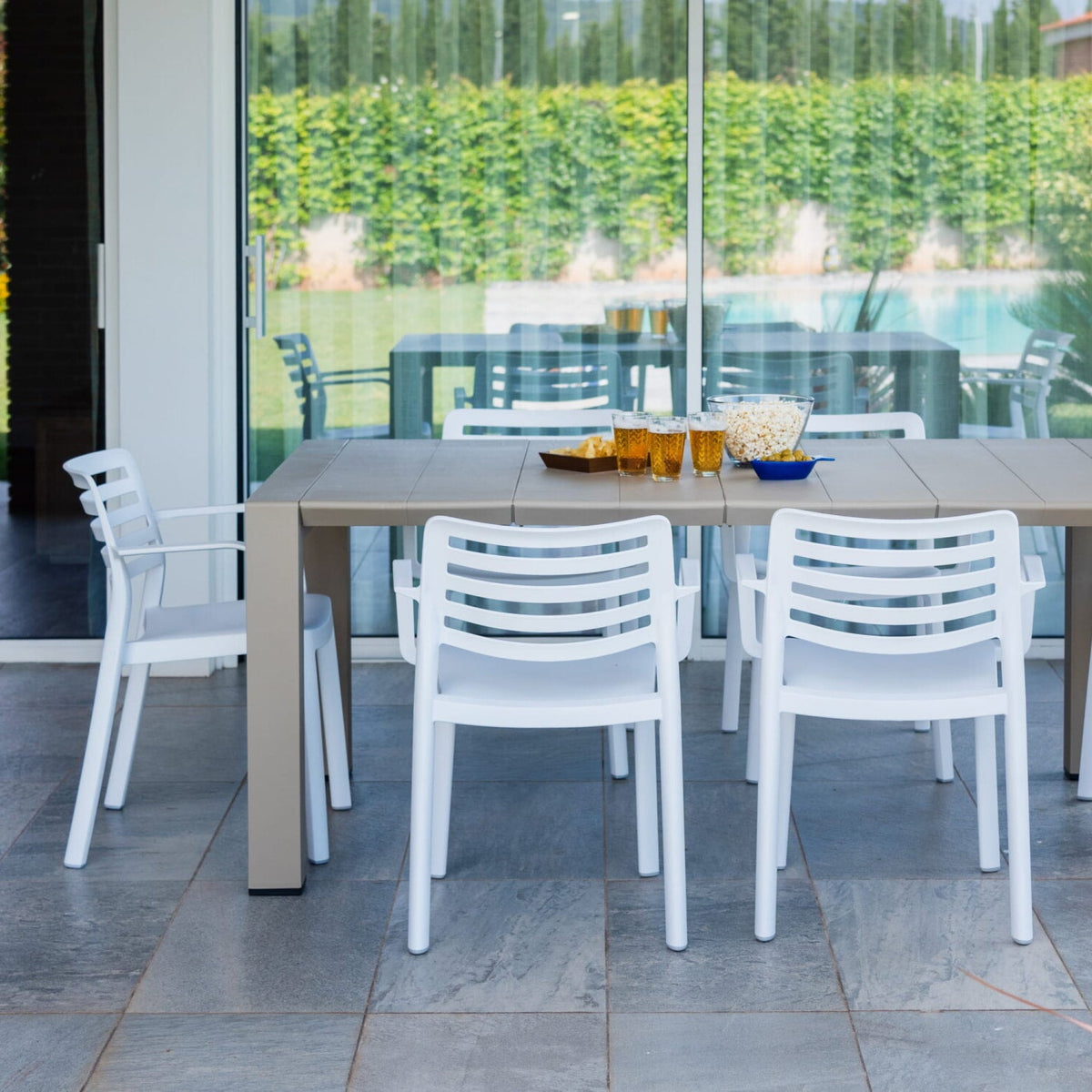 Garbar Wind Armchairs in White around a dining table on a covered patio