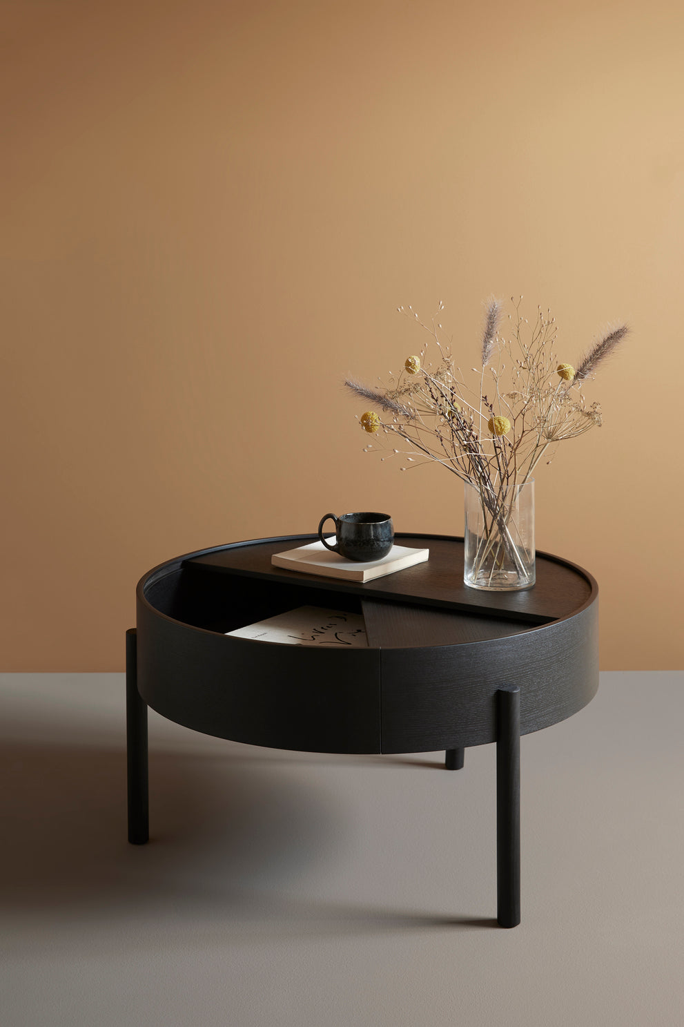 WOUD Arc Coffee Table in black painted ash, styled with dried flowers against a warm wall