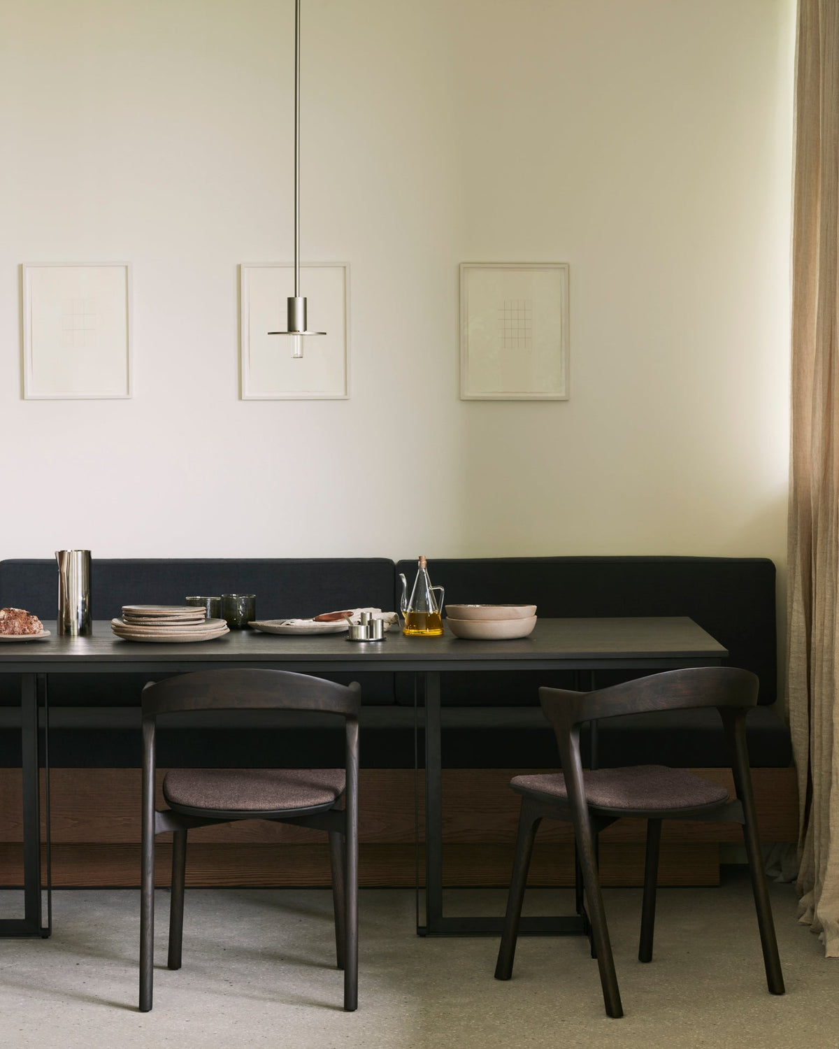 Ethnicraft Tacet Dining Table in dark brown teak with a banquette and dining chairs, styled in an interior setting