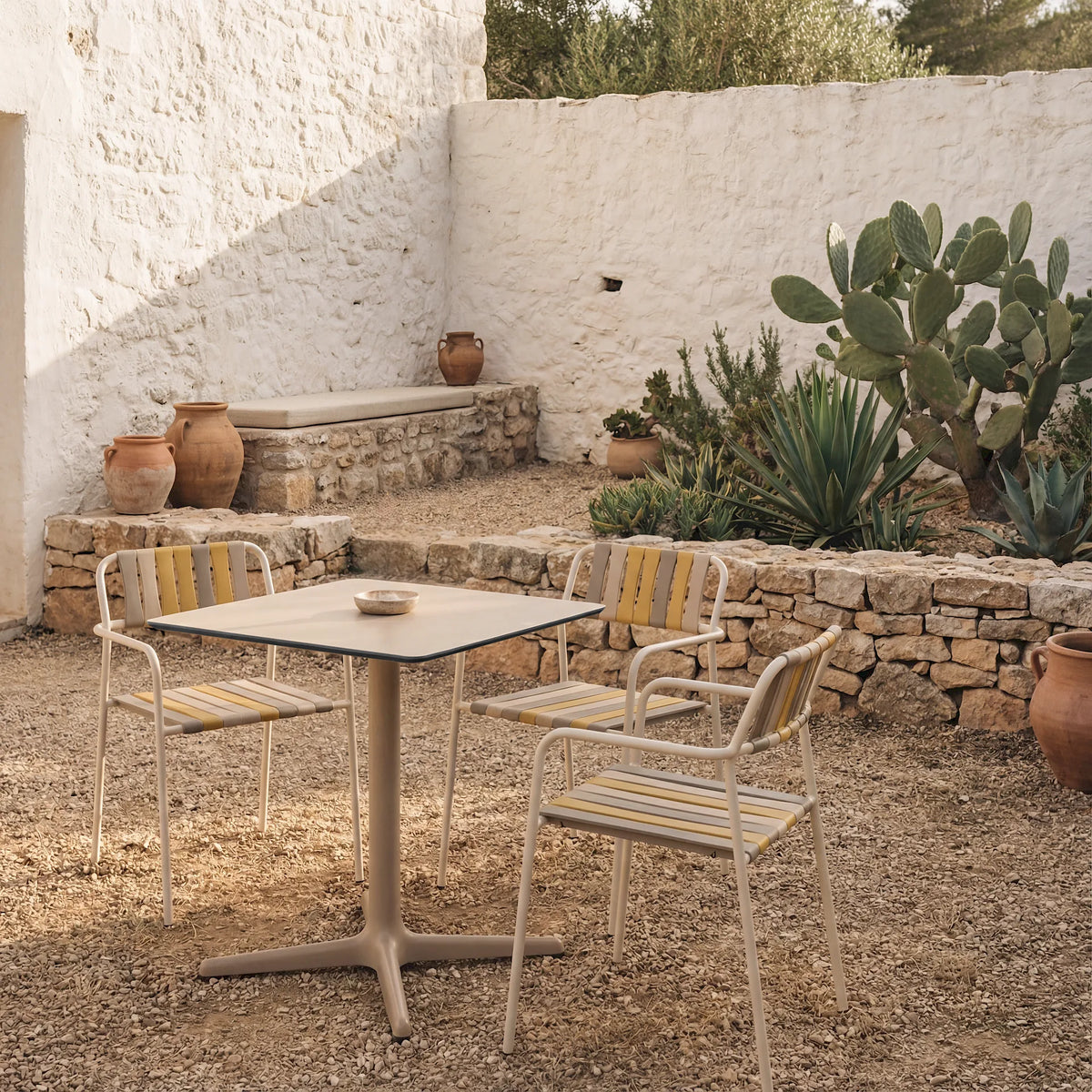 Resol Gelato armchairs in the Nocciola slat mix around a sand Toledo table in a whitewashed courtyard