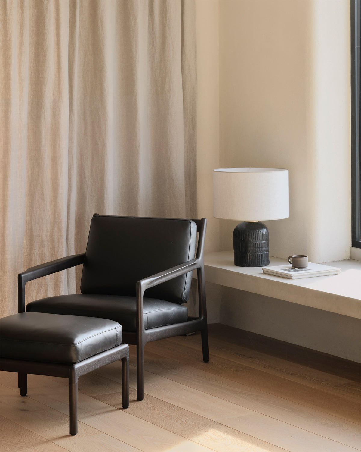 Ethnicraft Jack Footstool in Carbone Leather with the Jack Lounge Chair, styled in an interior setting, mahogany