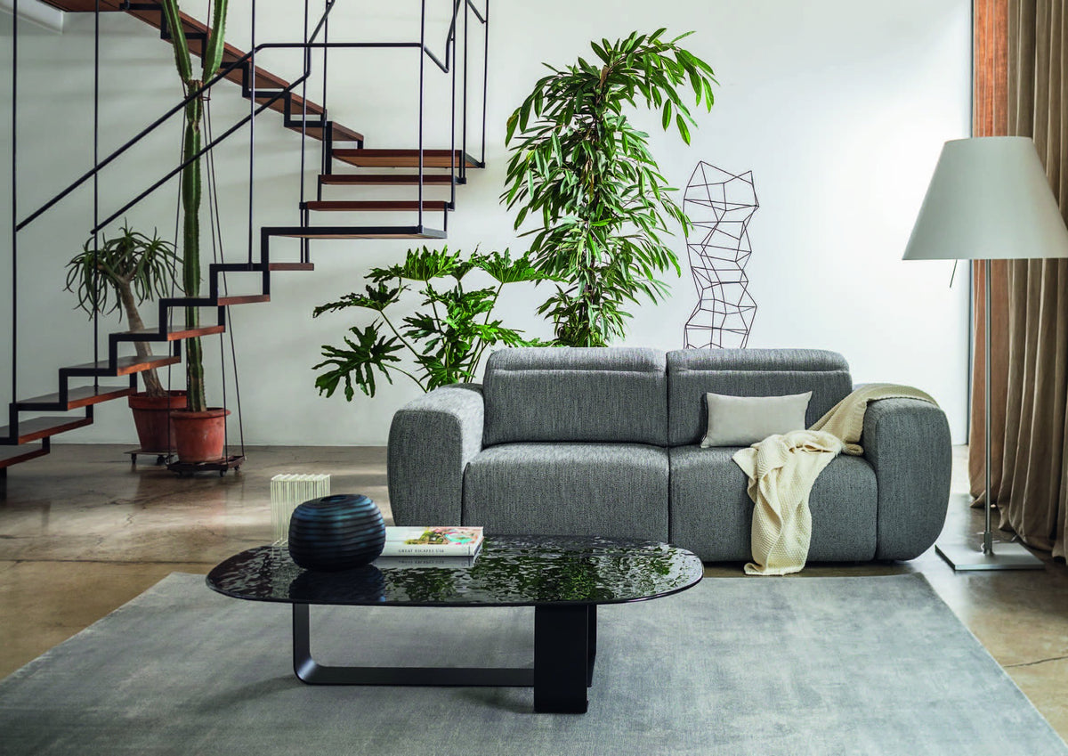 Luceplan Costanza Floor Lamp beside a gray sofa, styled in an interior setting