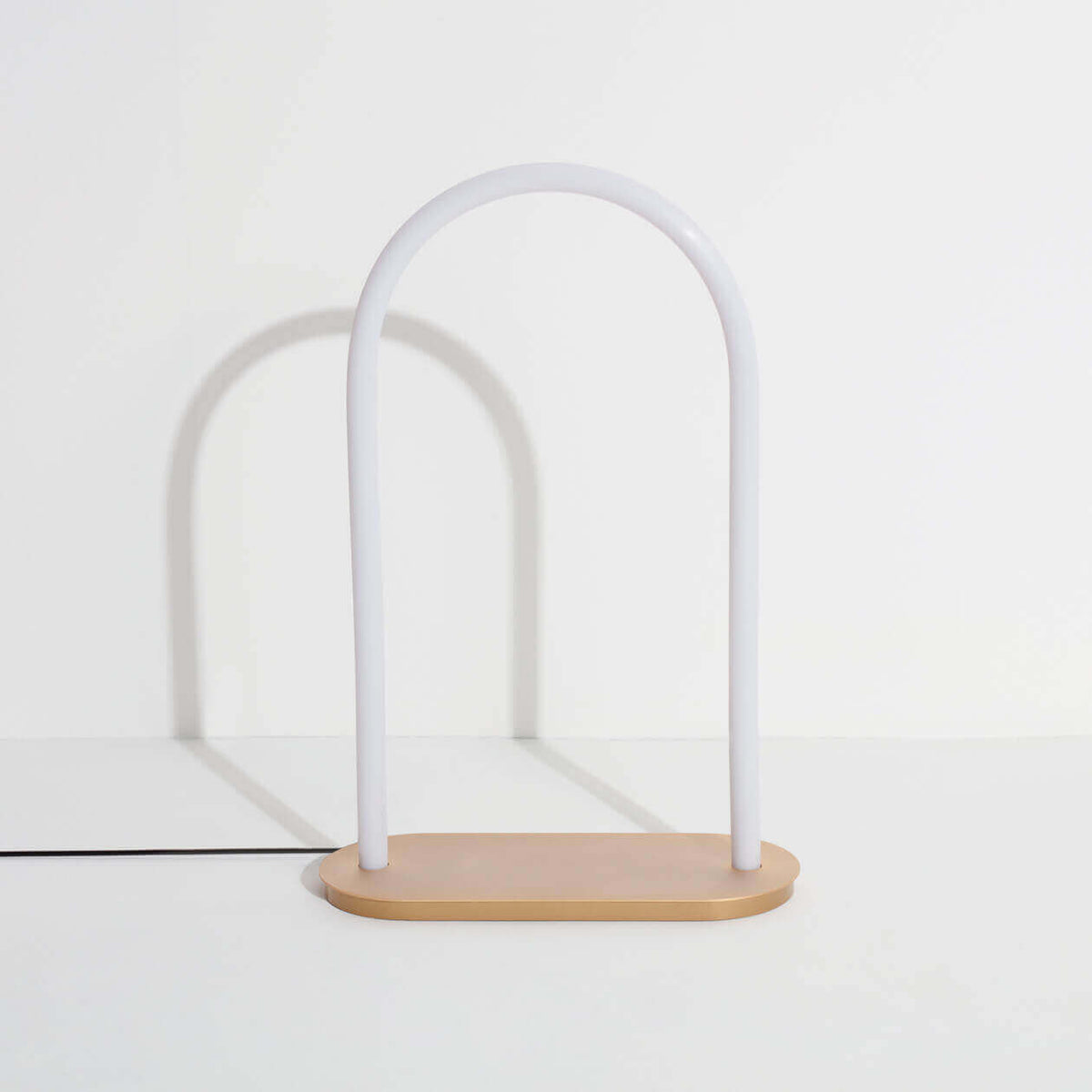 Petite Friture Unseen large table lamp, white glass arch on a brass base