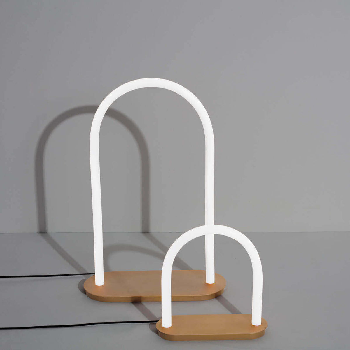 Two Petite Friture Unseen table lamps, white glass arches on brass bases