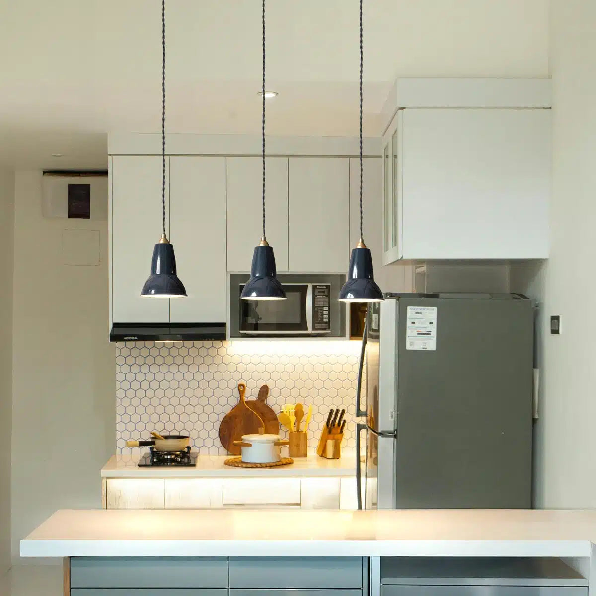 Three Anglepoise Original 1227 Brass pendants in Jet Black above a kitchen counter